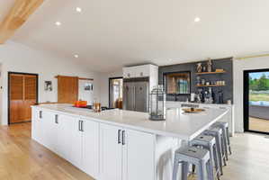 Open-concept kitchen featuring an expansive central island with a solid surface countertop, integrated cooktop, and casual dining space