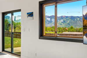 Expansive mountain scenery framed by a large wood-framed window with a black trim