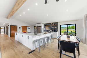 Spacious kitchen with a large central island, recessed lighting, wood-finish flooring, and a sliding glass door