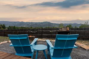 Outdoor fire pit area featuring a gravel surface, stone accents, and a wood fence border
