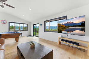 Bright interior space featuring vaulted ceilings, recessed lighting, wood-finish flooring, and expansive windows