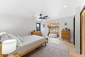 Bedroom featuring light wood-finish flooring, a contemporary ceiling fan, and white walls