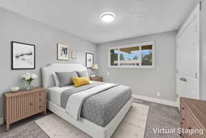 Bedroom featuring neutral gray walls and carpeting, a window with white blinds, a white paneled door, and a flush-mount ceiling light