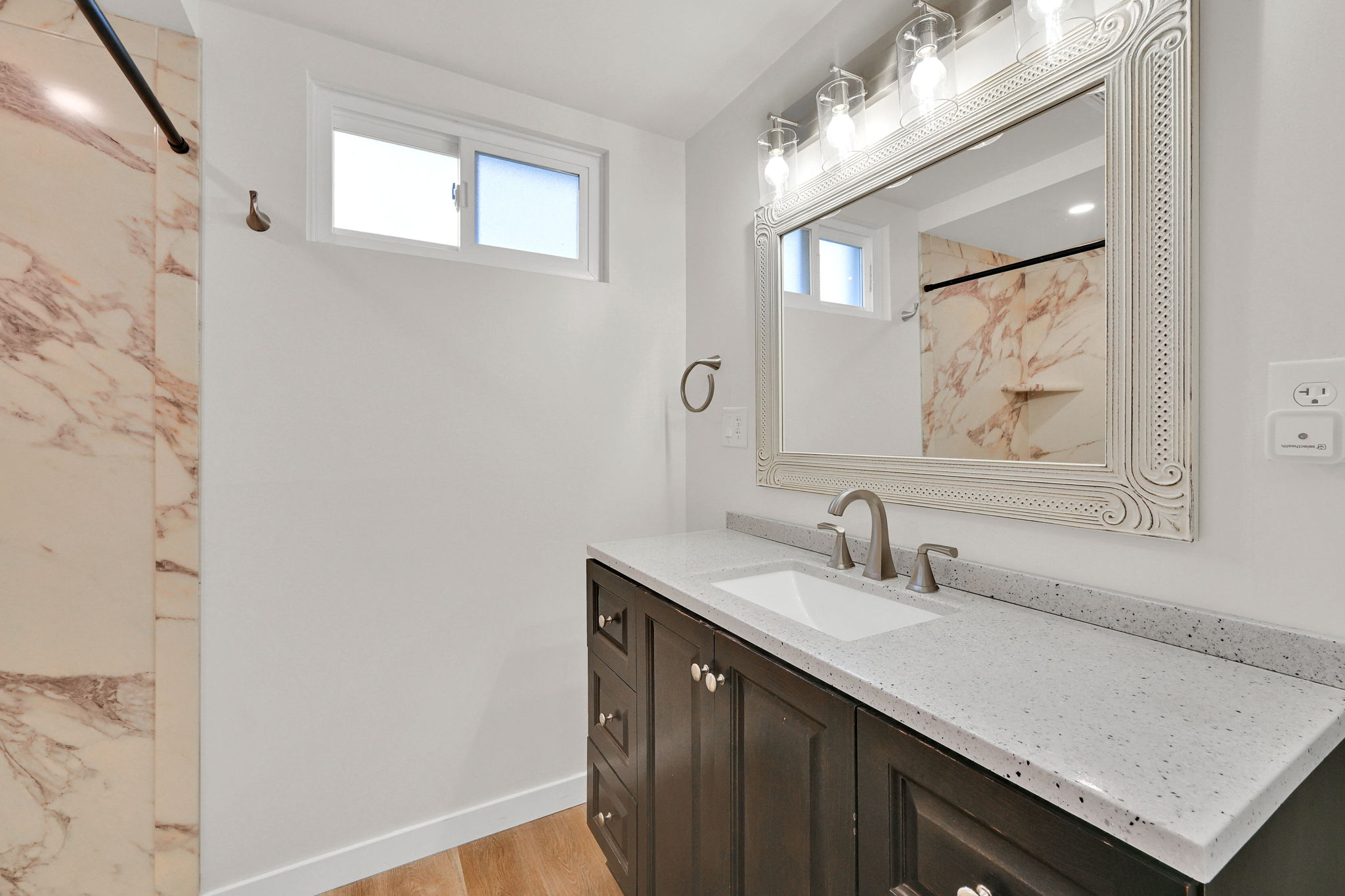 Bathroom featuring a dark wood vanity with a light speckled countertop, an undermount sink, and a framed mirror