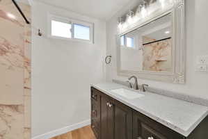 Bathroom featuring a dark wood vanity with a light speckled countertop, an undermount sink, and a framed mirror