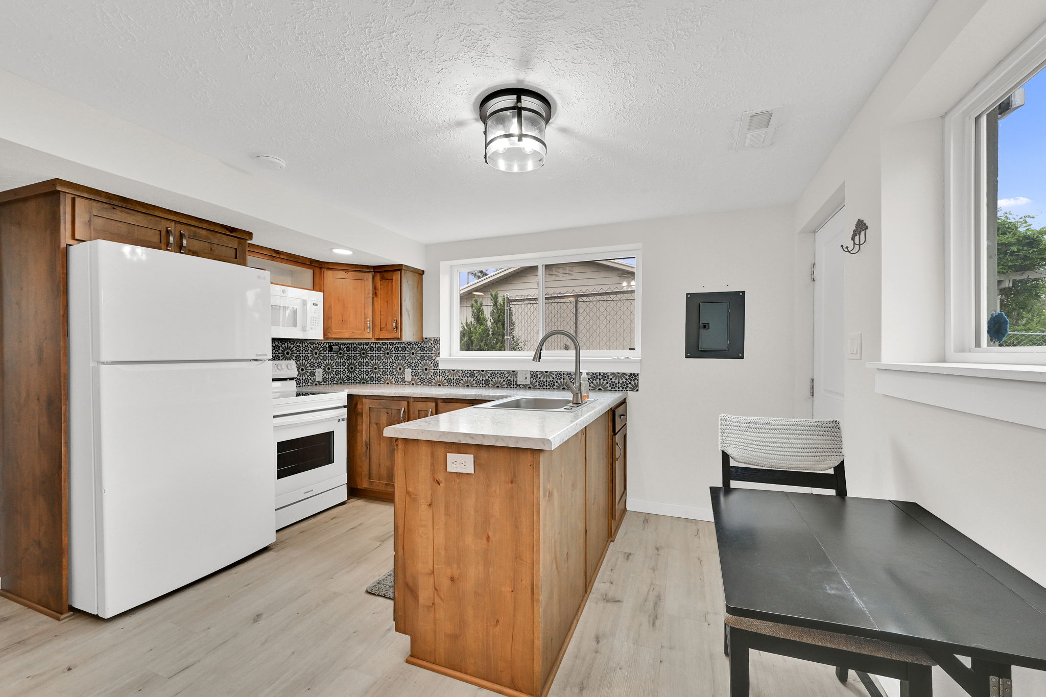 Kitchen featuring wood cabinetry, light-toned countertops, patterned tile backsplash, and light-finish flooring