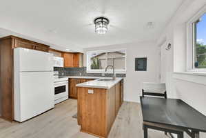 Kitchen featuring wood cabinetry, light-toned countertops, patterned tile backsplash, and light-finish flooring