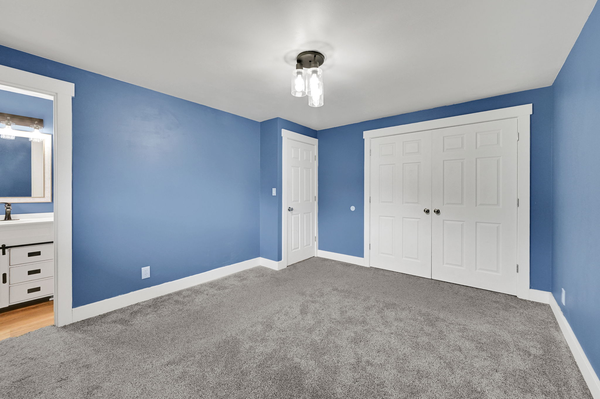 Spacious room featuring plush gray carpeting, white baseboards, a white six-panel bifold closet, and a contemporary ceiling light fixture