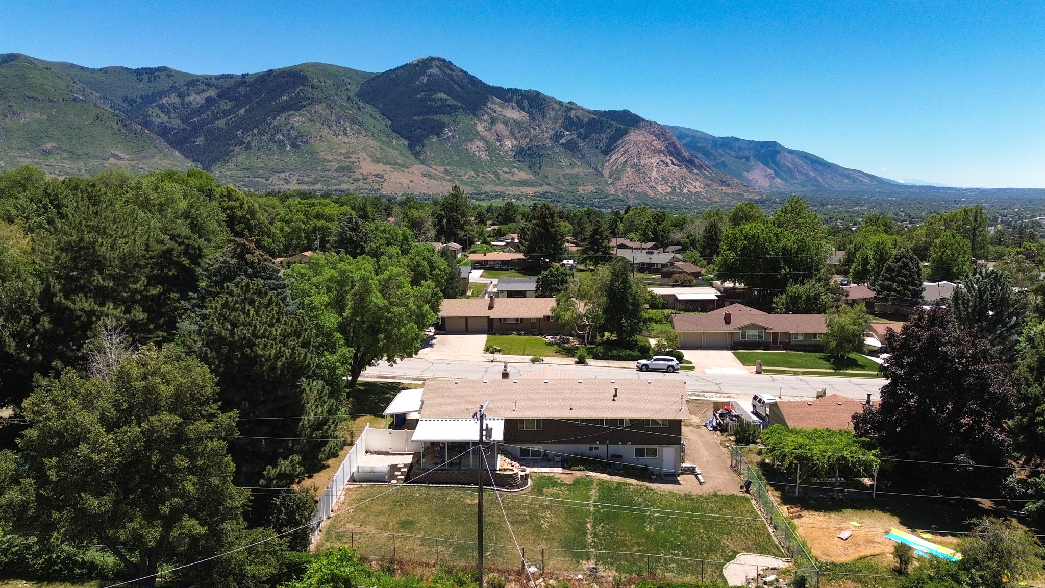 Elevated aerial perspective showcasing a single-family residence with a mountain backdrop and mature trees