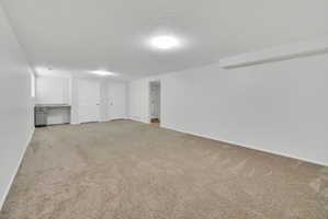 Spacious carpeted room featuring a built-in desk with a light-colored countertop, two panel doors, and recessed lighting