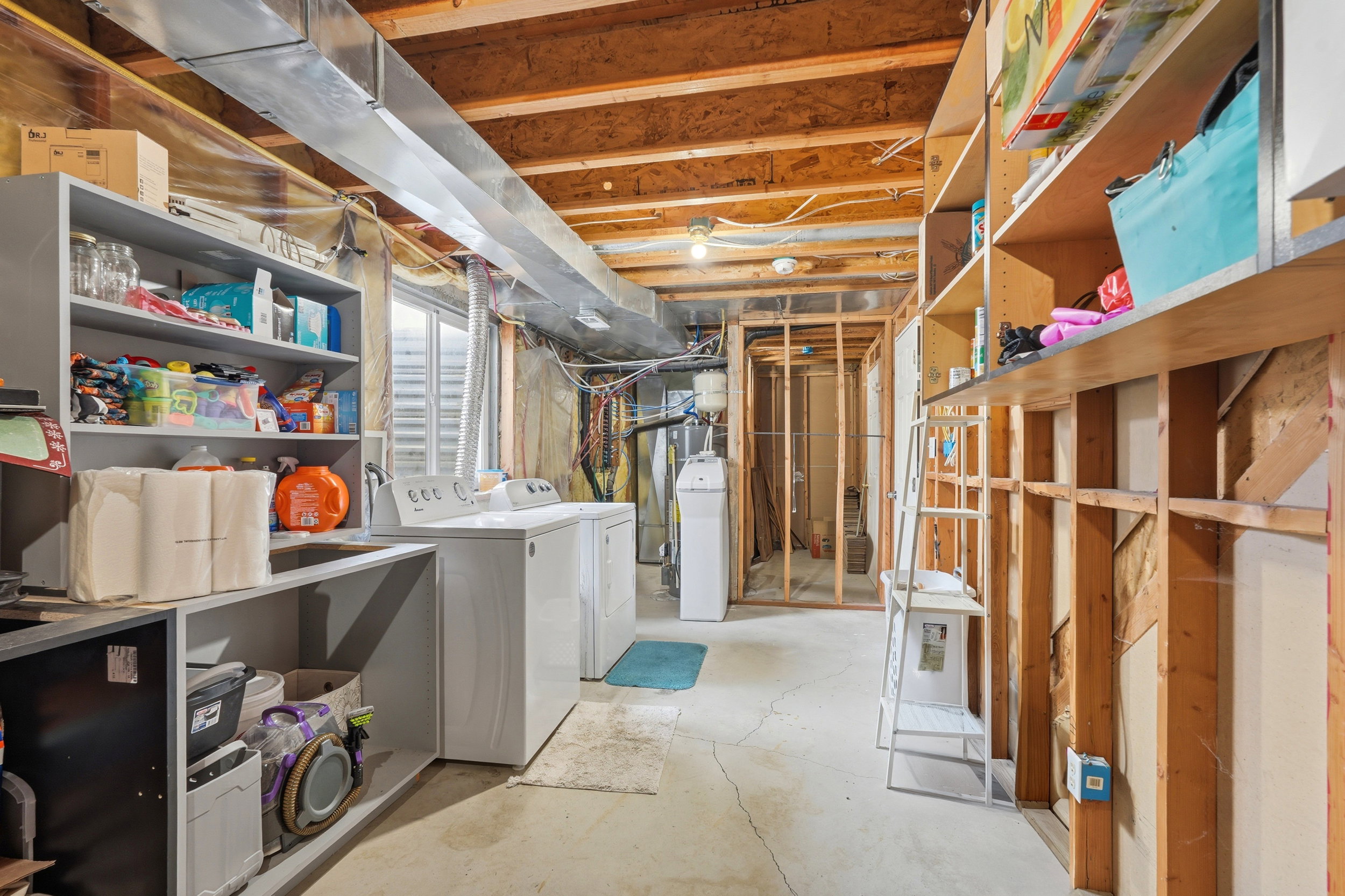 Utility area featuring exposed wood ceiling joists and concrete flooring