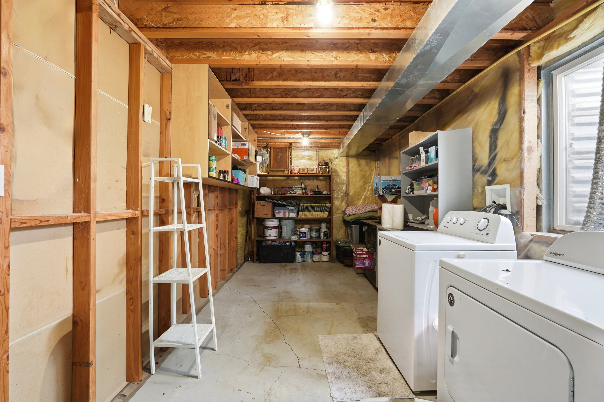 Unfinished basement with exposed wooden joists and concrete flooring