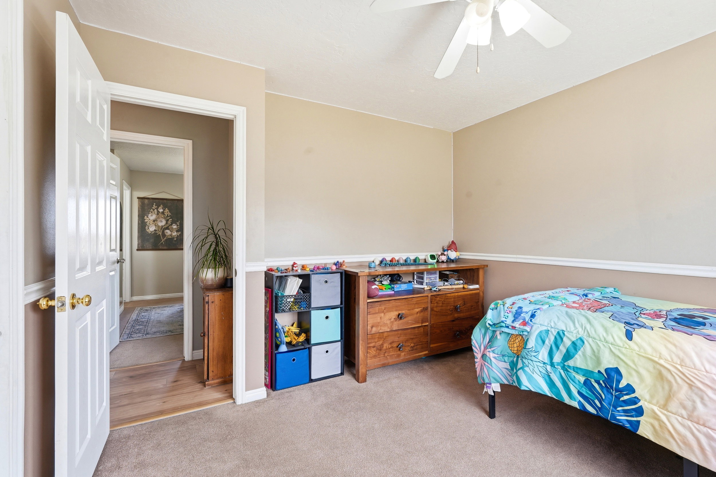 Carpeted room with neutral walls, white trim, and a ceiling fan