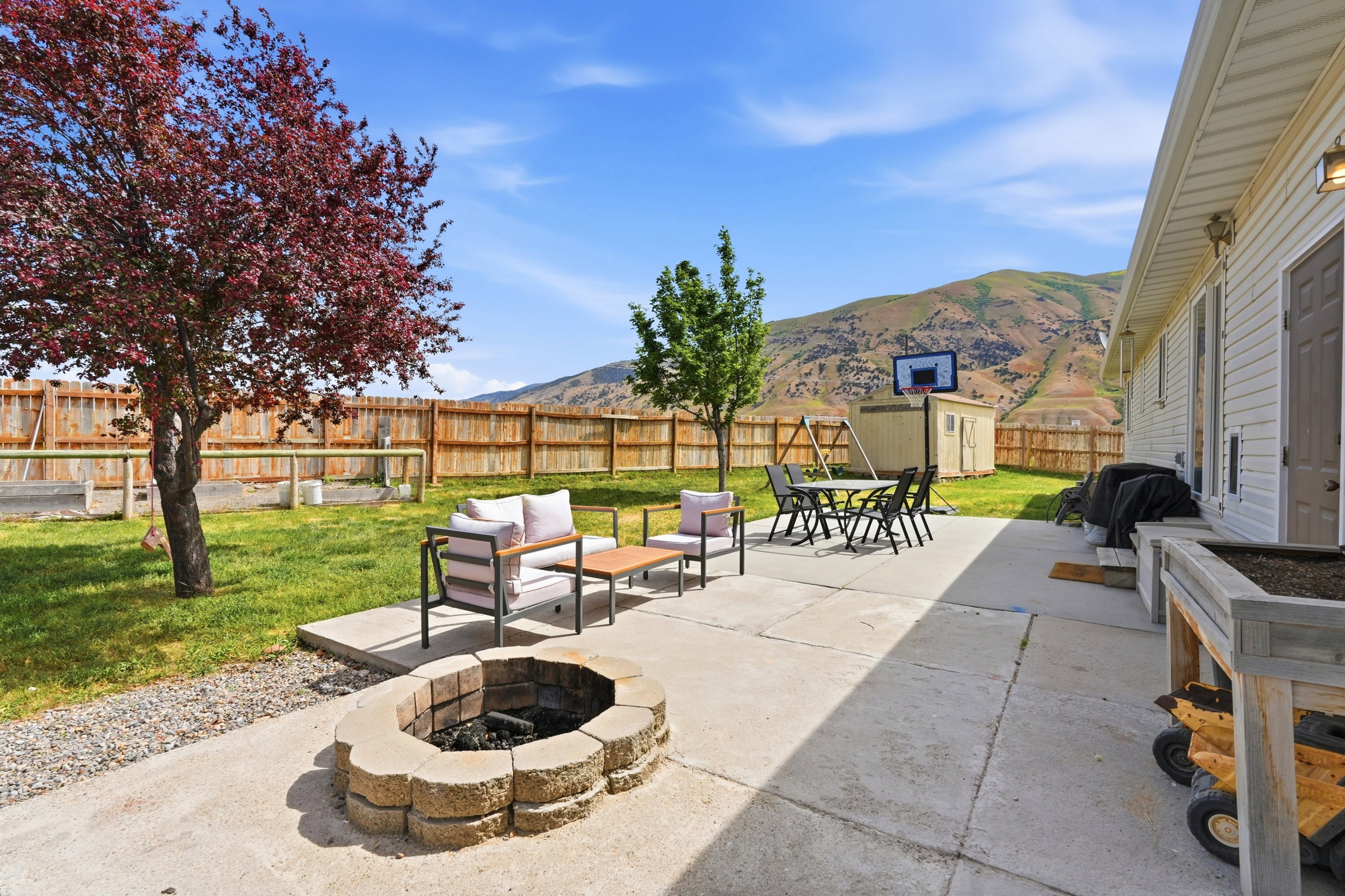 Expansive backyard featuring a stone fire pit, a concrete patio, and a manicured lawn