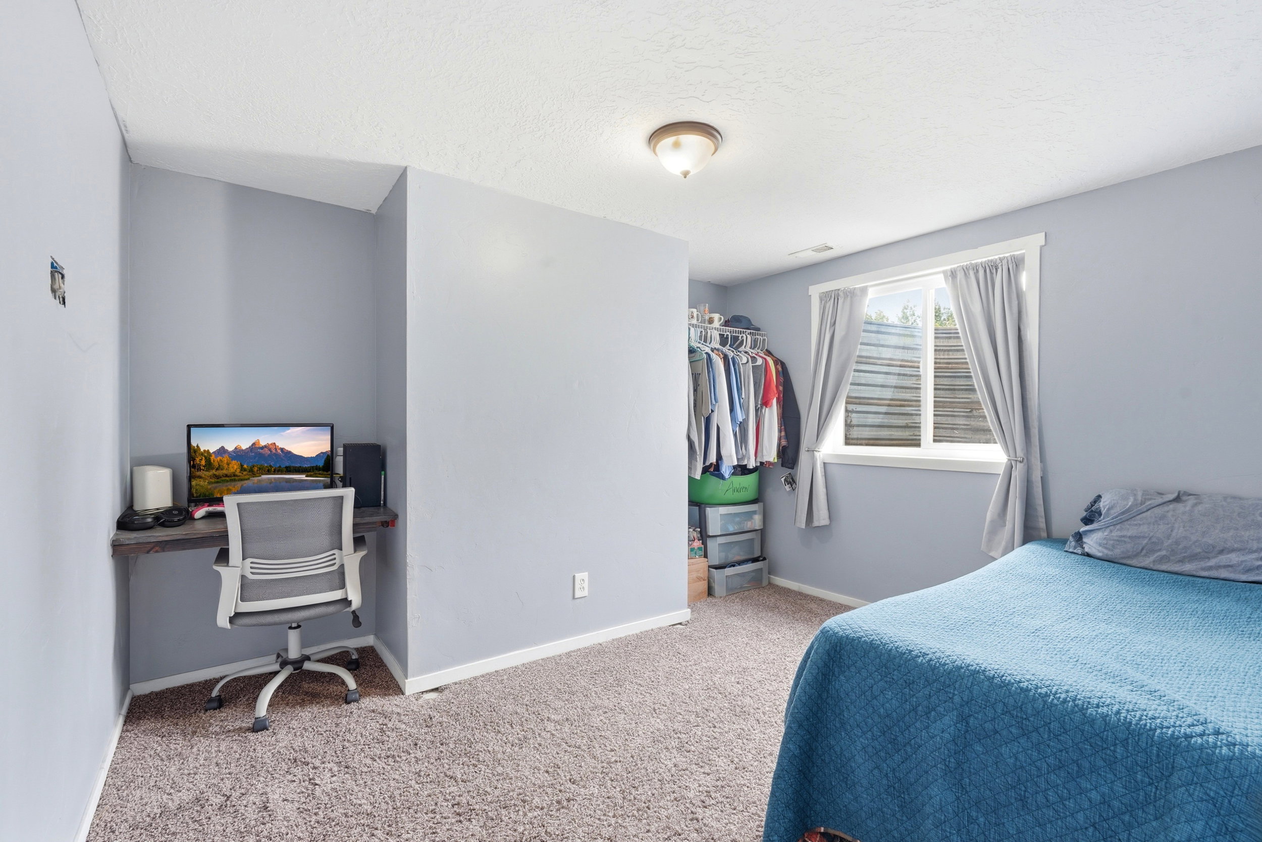 Carpeted room with a built-in wood-finish desk, a window with white trim, and an open closet system