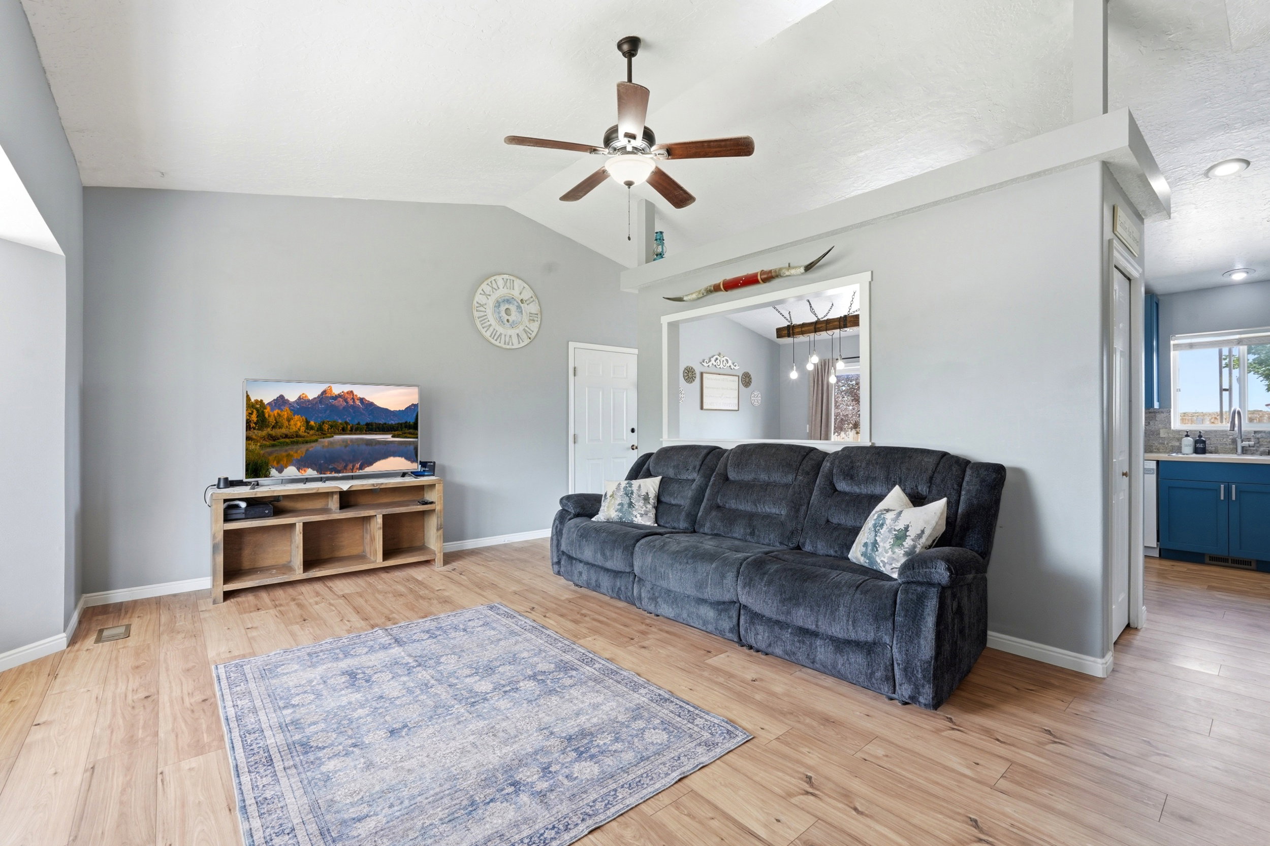 Spacious living area featuring wood-finish flooring, vaulted ceilings, and a ceiling fan