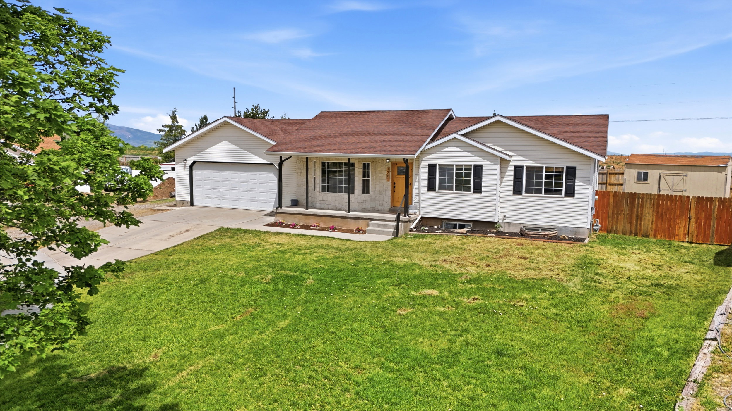 Single-story residence featuring white siding, a brown shingle roof, and an attached two-car garage