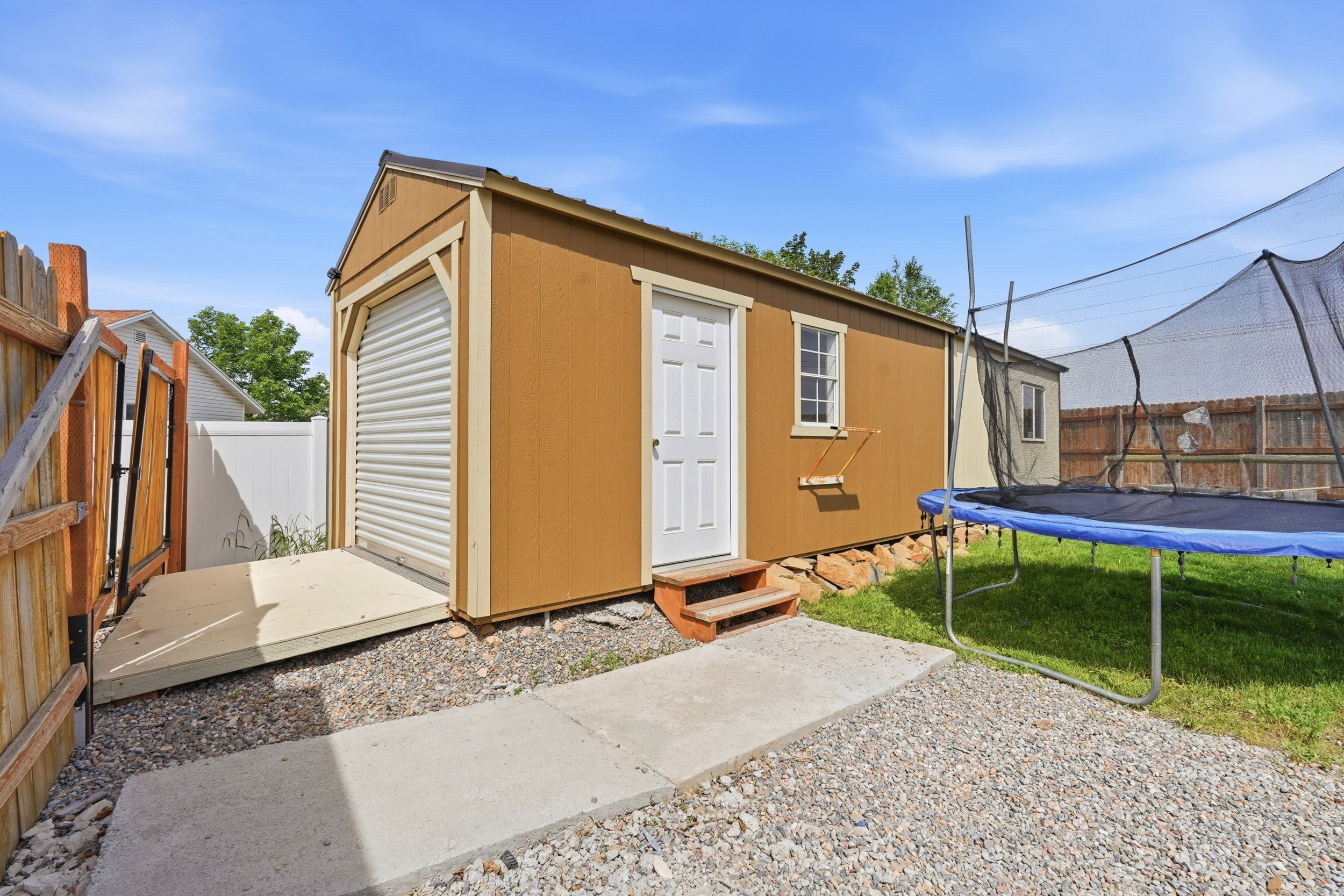 Detached storage shed featuring a rolling garage door, pedestrian entry door, and a side window
