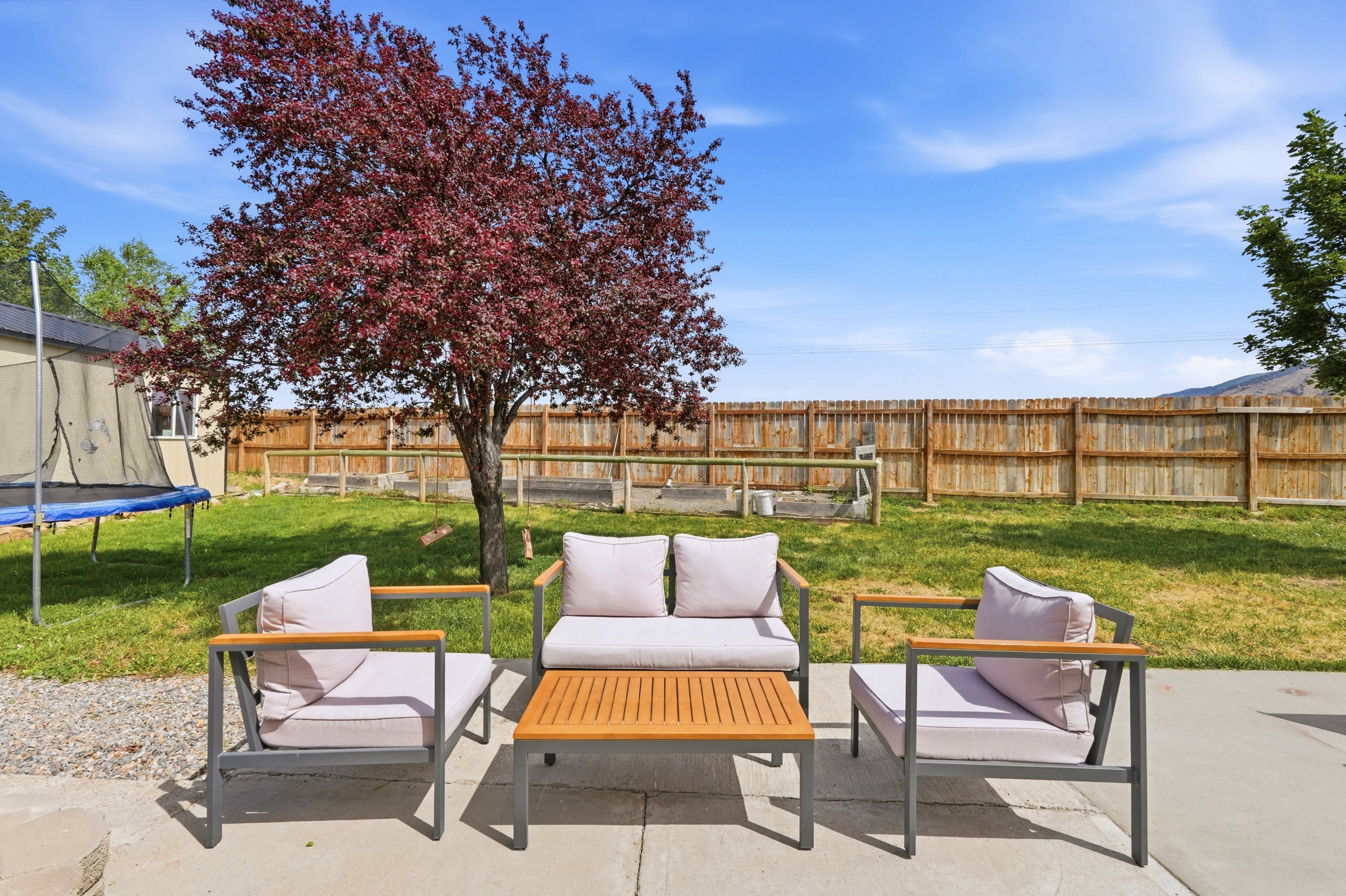 Expansive backyard featuring a concrete patio, a mature tree, and a wooden privacy fence