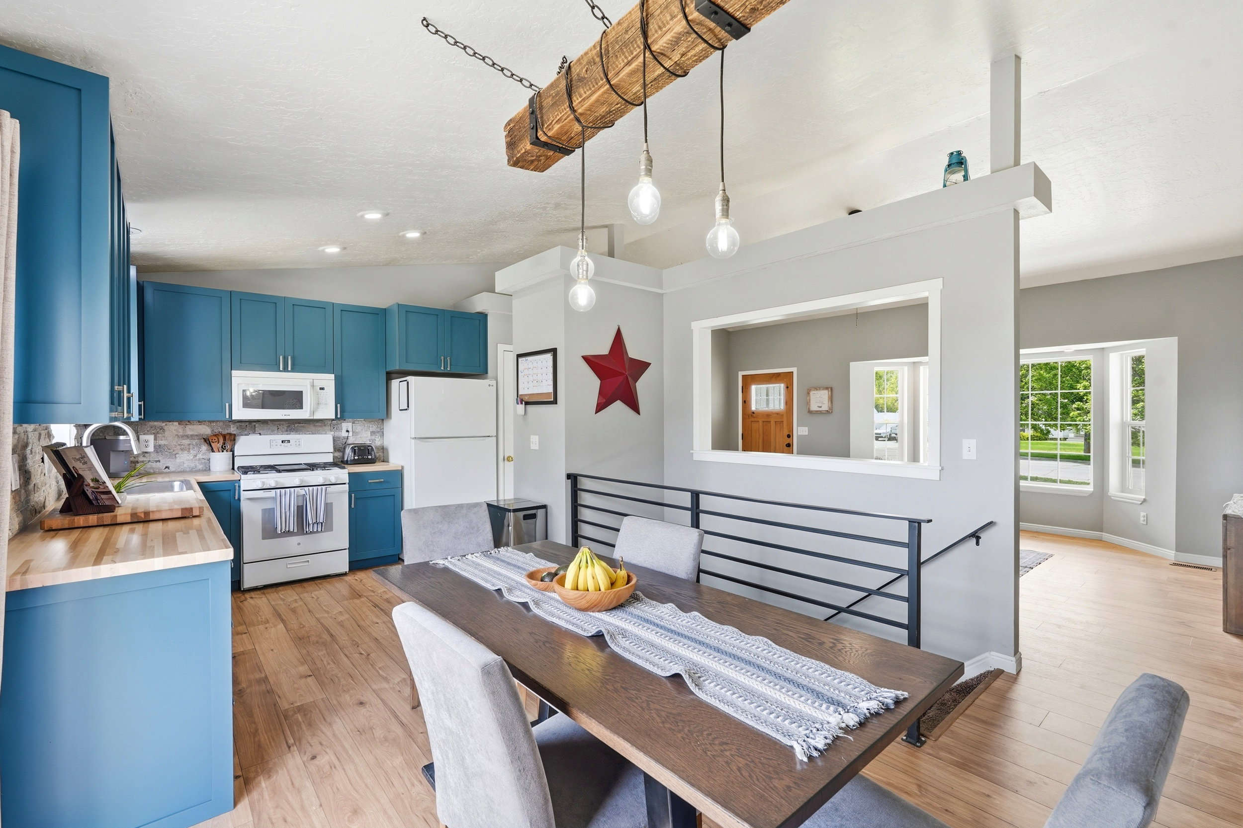 Kitchen featuring teal cabinetry, wood-finish flooring, and white appliances