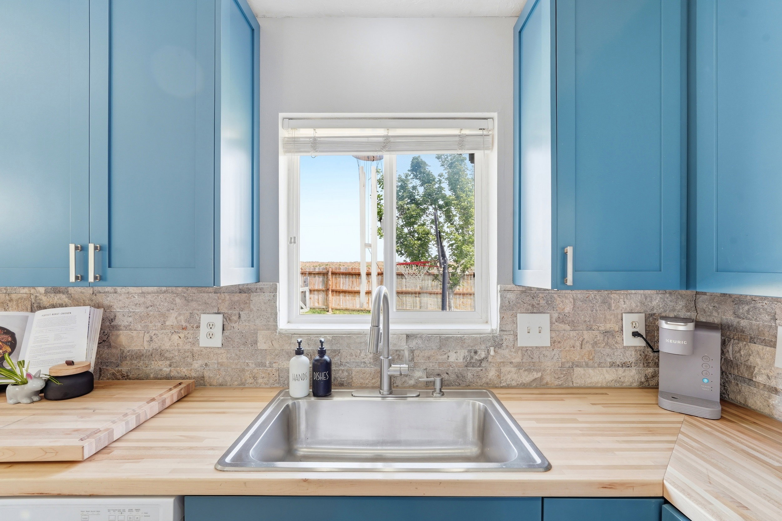 Kitchen sink area featuring a stainless steel undermount sink, a chrome pull-down faucet, and light wood countertops