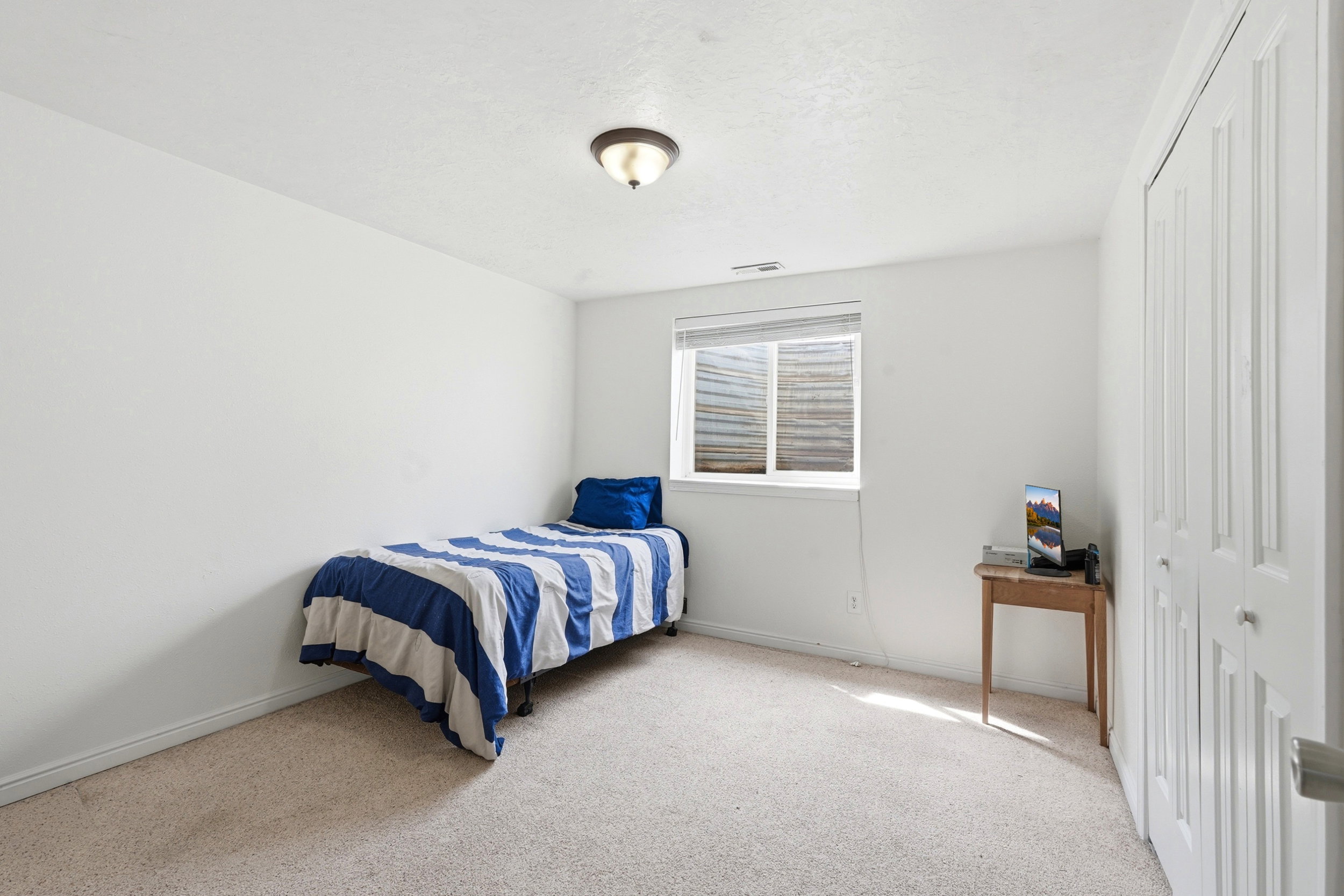 Carpeted room featuring a single window with blinds, white walls, and a bi-fold closet
