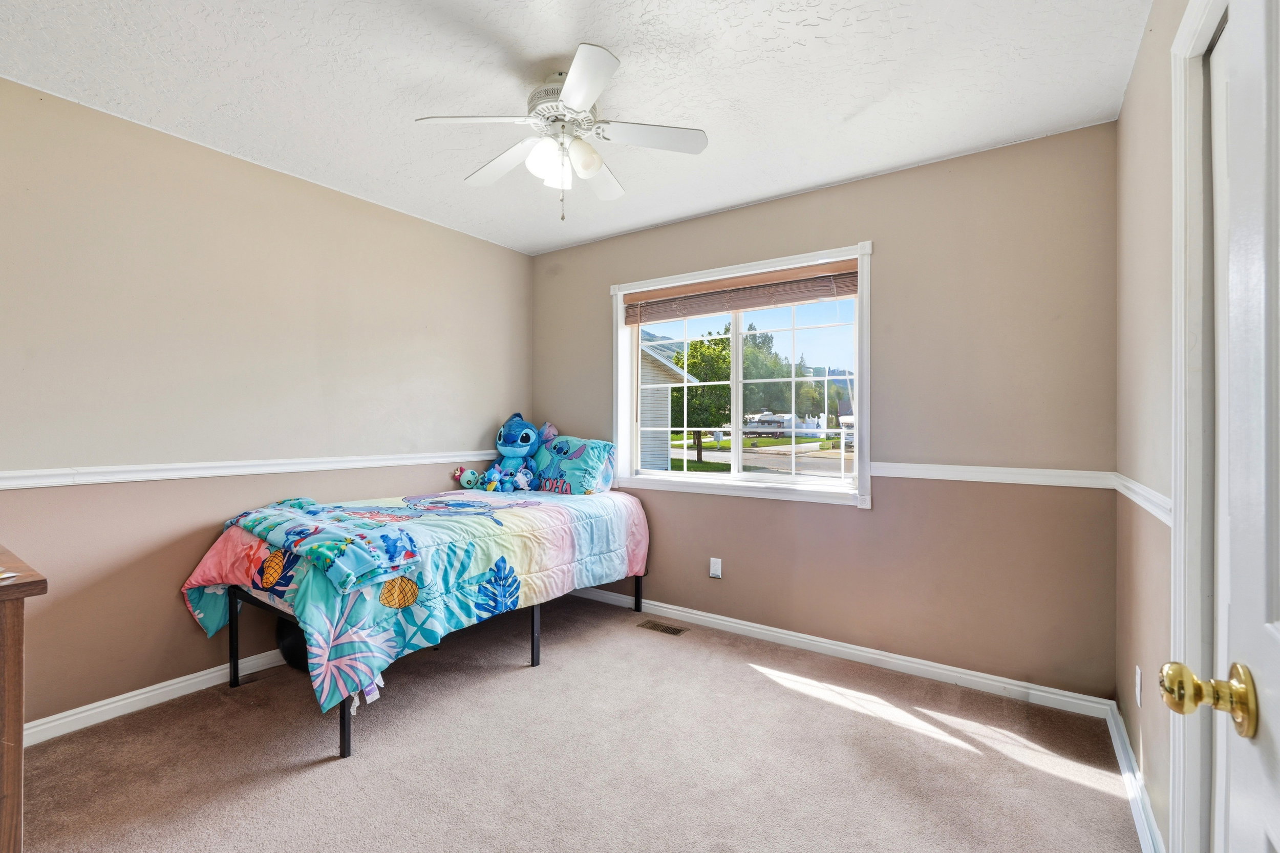 Carpeted room with a ceiling fan, a window with horizontal blinds, and two-tone painted walls featuring white trim