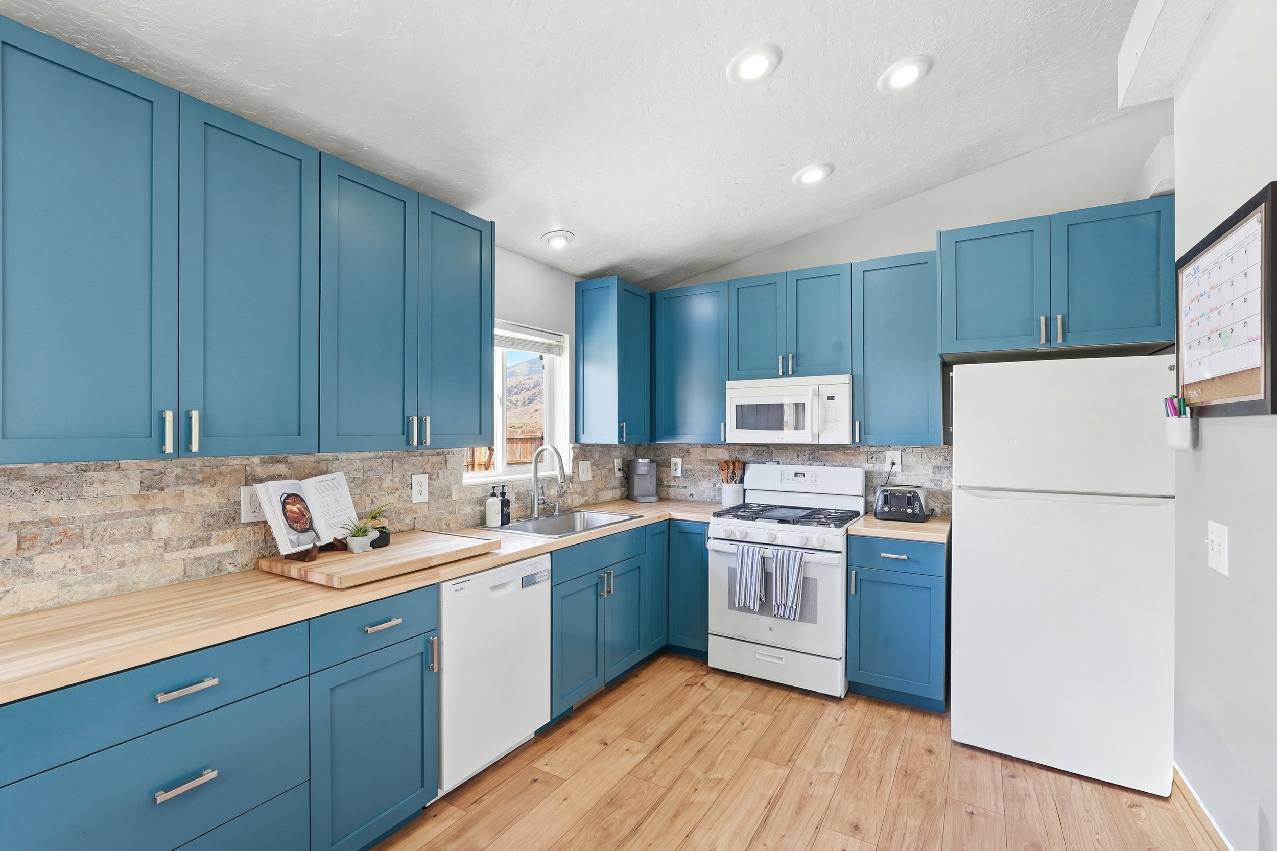 Kitchen featuring blue shaker-style cabinetry, wood-finish countertops, and a stacked stone backsplash