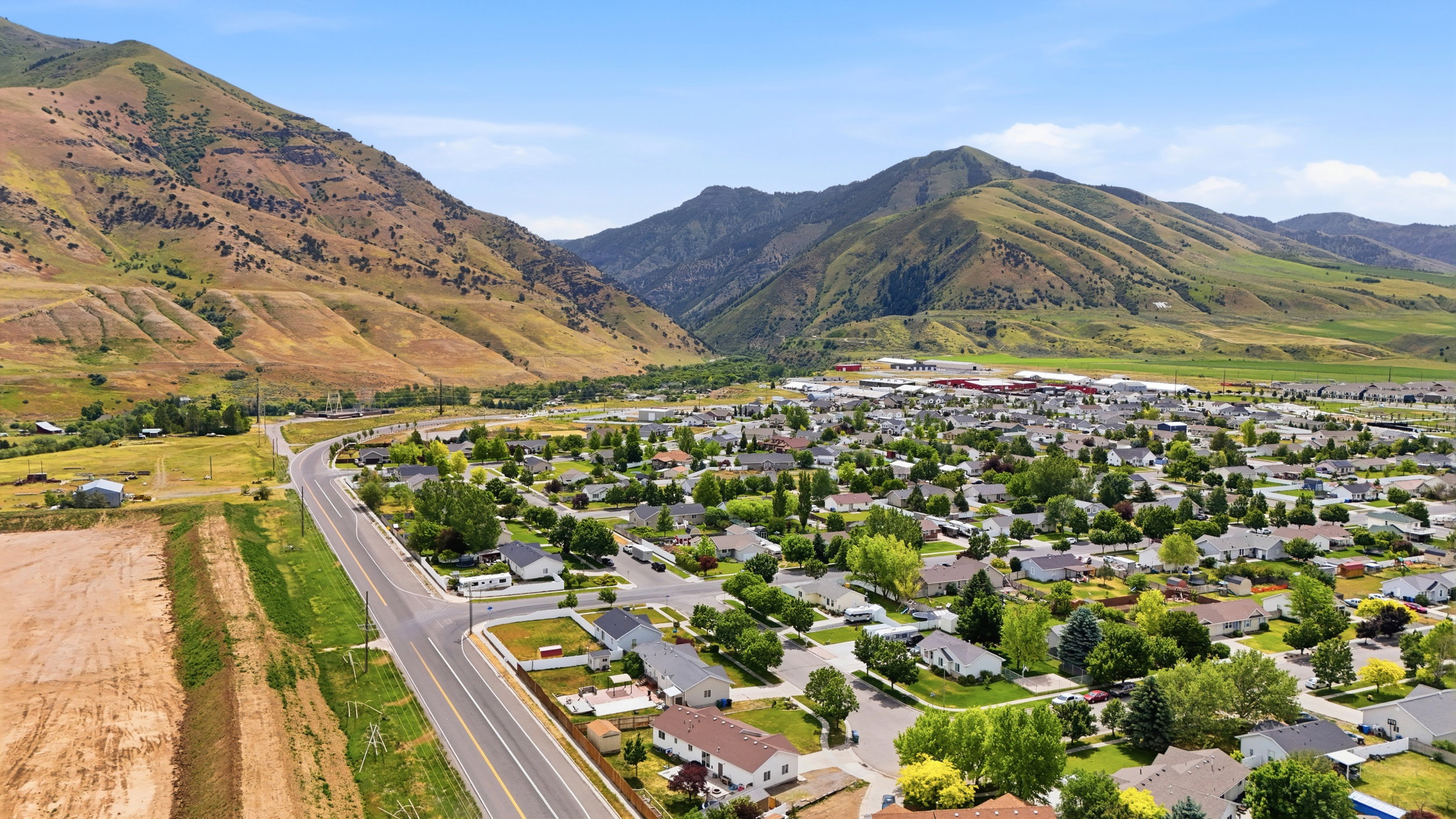 Expansive aerial perspective showcasing a residential community nestled against a backdrop of verdant mountains