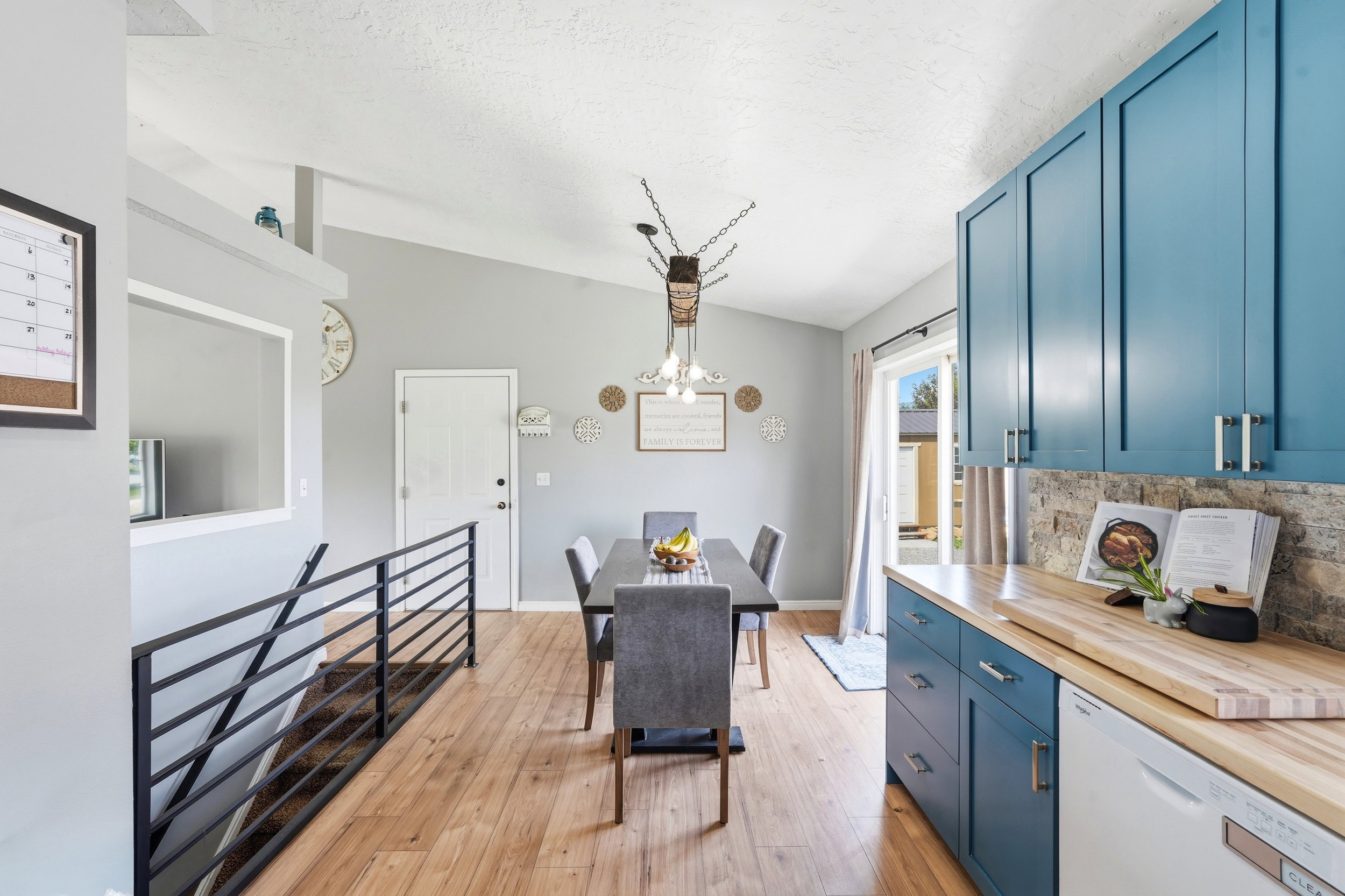 Open-concept kitchen and dining area featuring vaulted ceilings, wood-finish flooring, and a modern light fixture