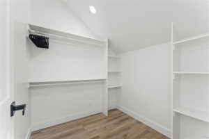Attic closet featuring wood-finish flooring and integrated shelving