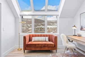 Bright room featuring a large skylight system, three expansive windows, clean white walls, light wood-finish flooring, and a built-in desk
