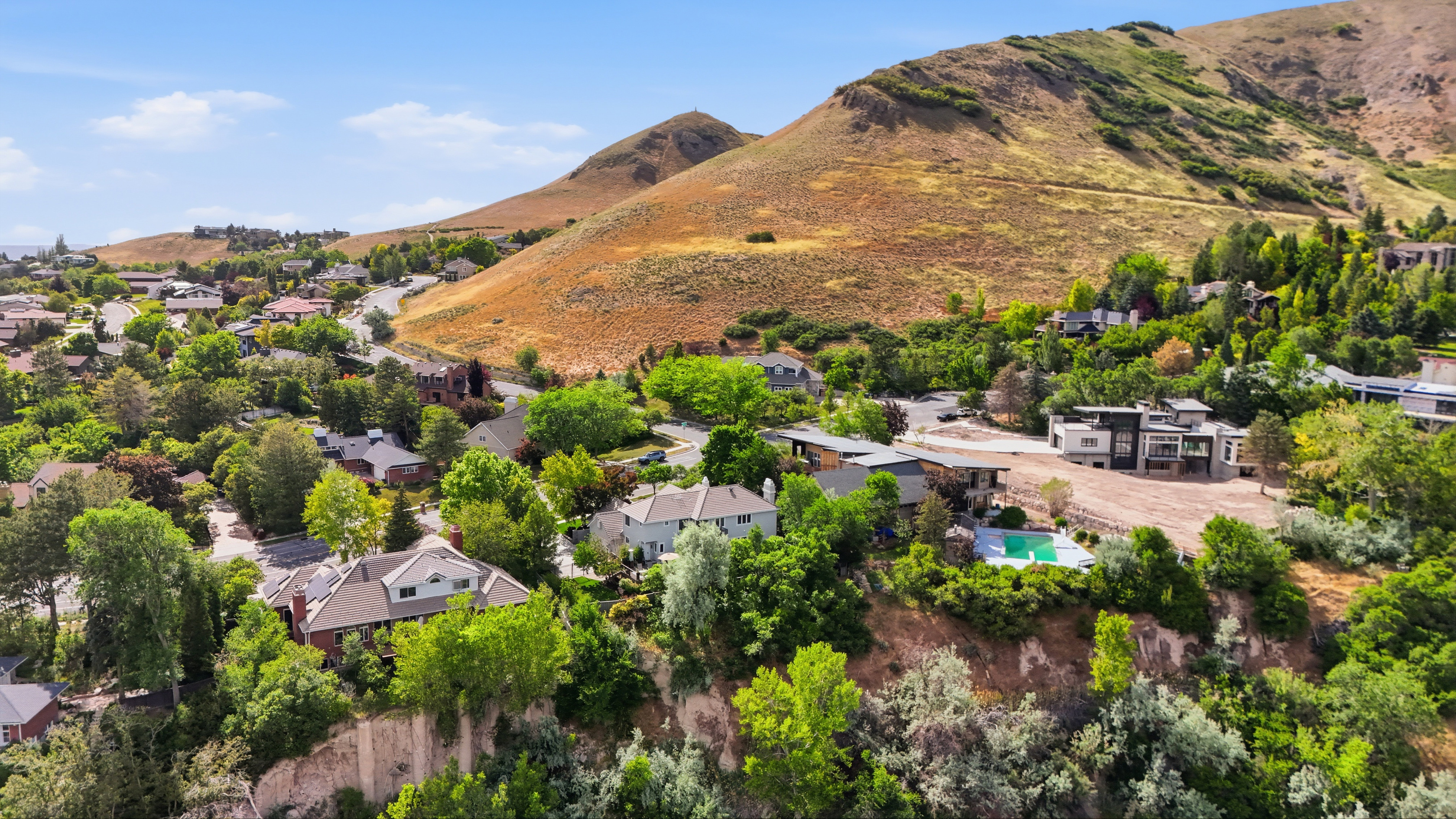 Residential neighborhood situated on a hillside with surrounding mature trees and mountain terrain