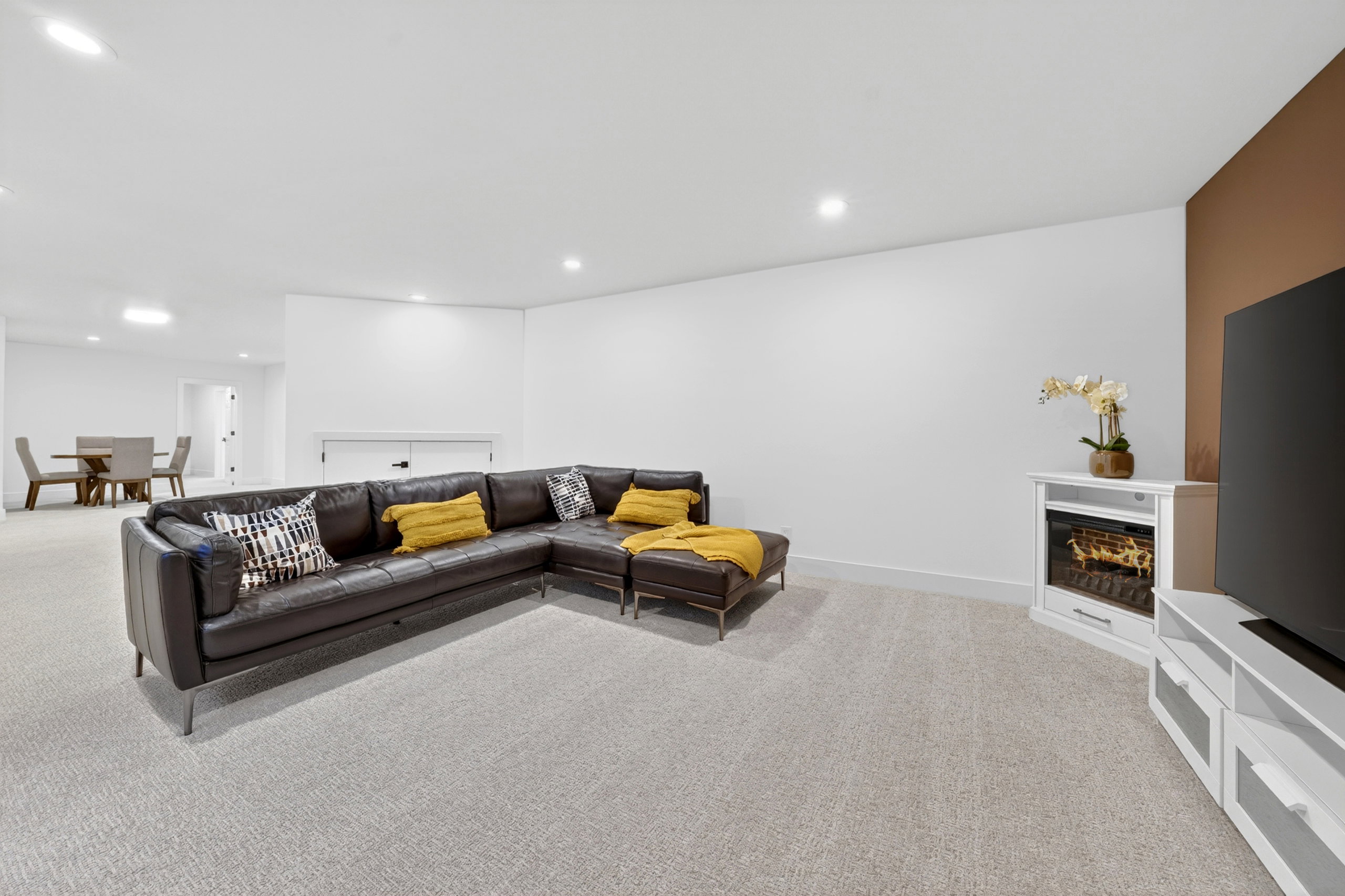 Spacious interior featuring light gray carpeting, recessed lighting, and a white baseboard trim