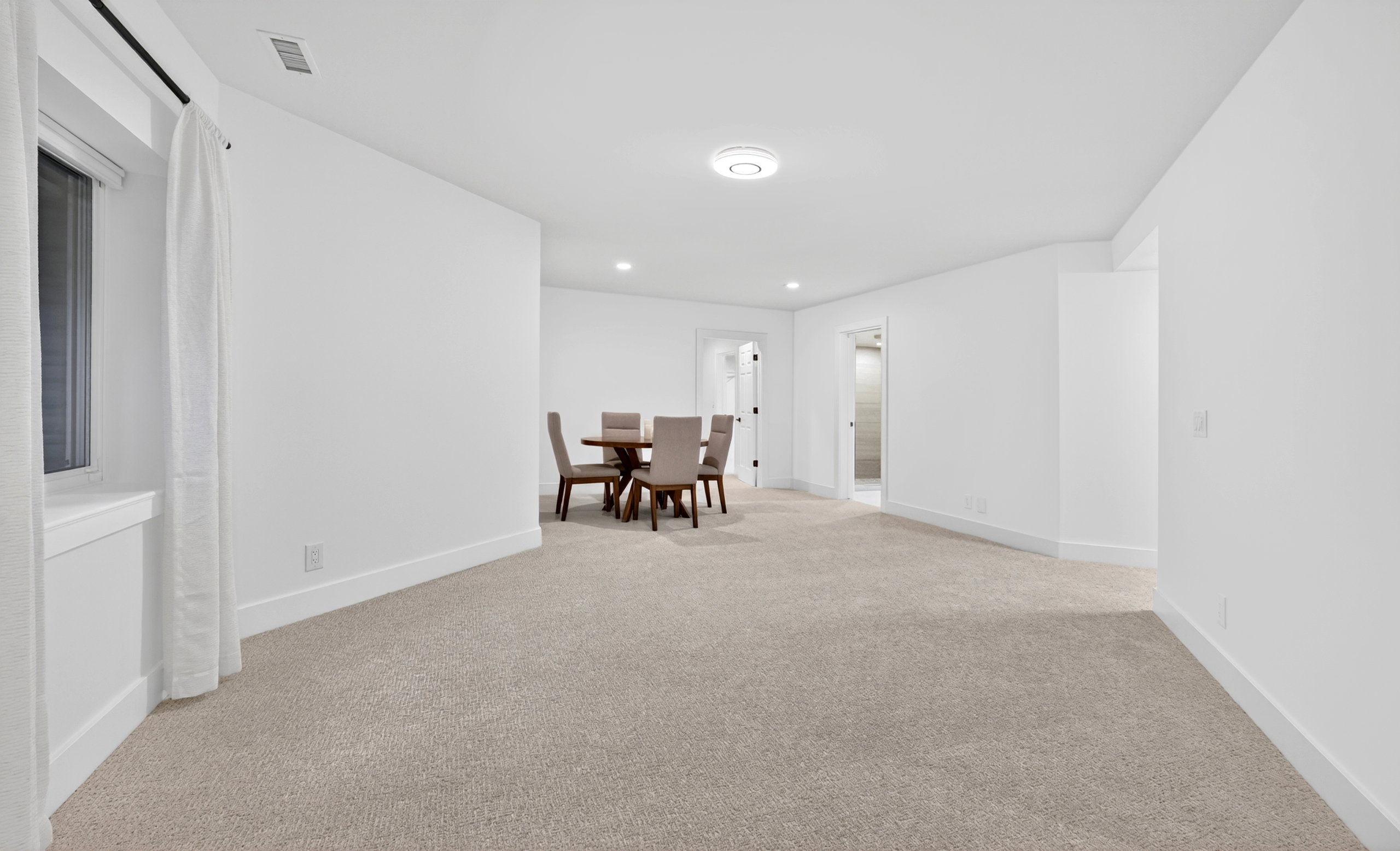 Spacious room featuring light-colored carpeting, white walls, and a round overhead light fixture