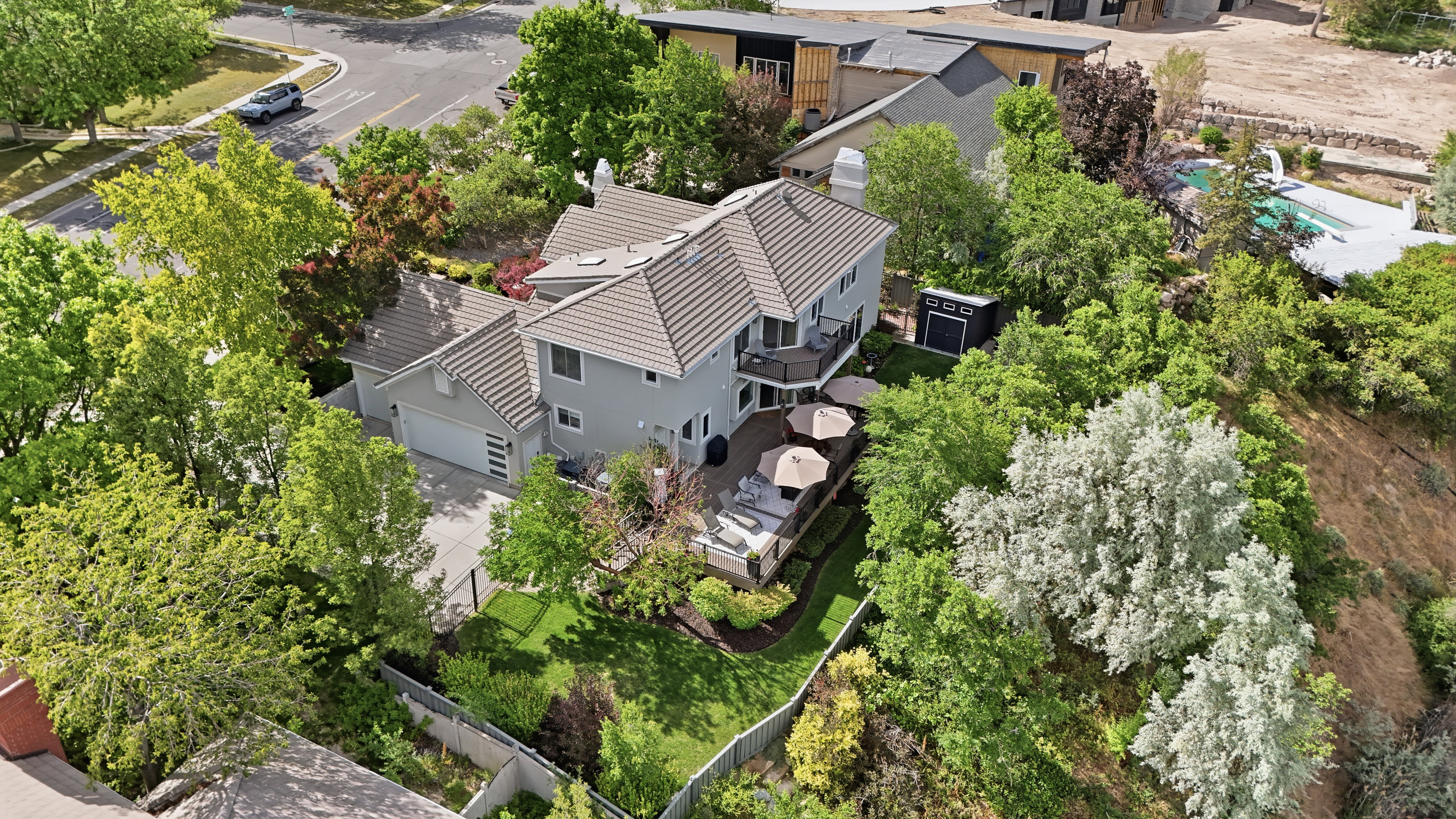 Contemporary residence with a tiled roof, multi-level deck, integrated garage, and lush surrounding landscaping