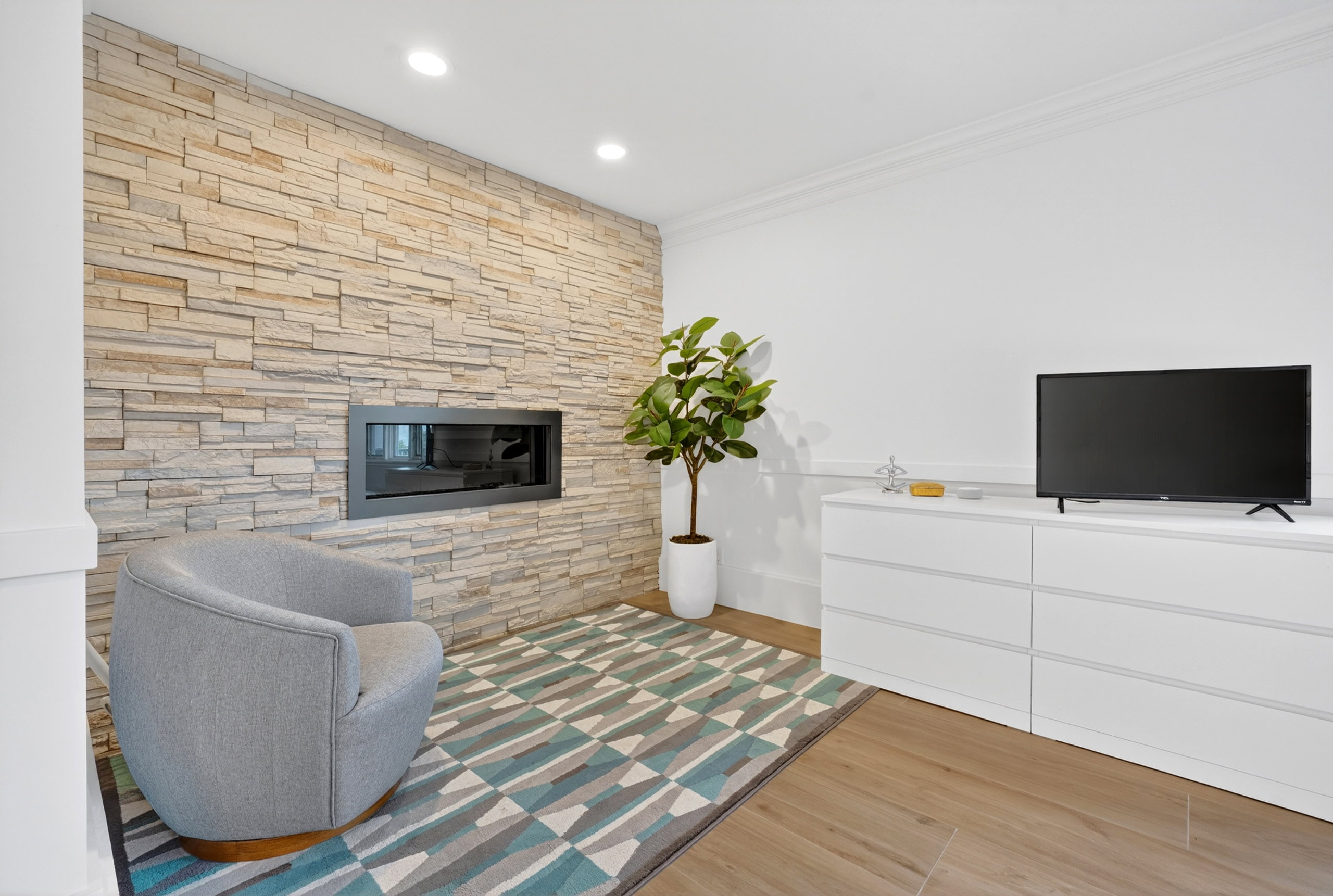 Stacked stone accent wall with an integrated modern fireplace