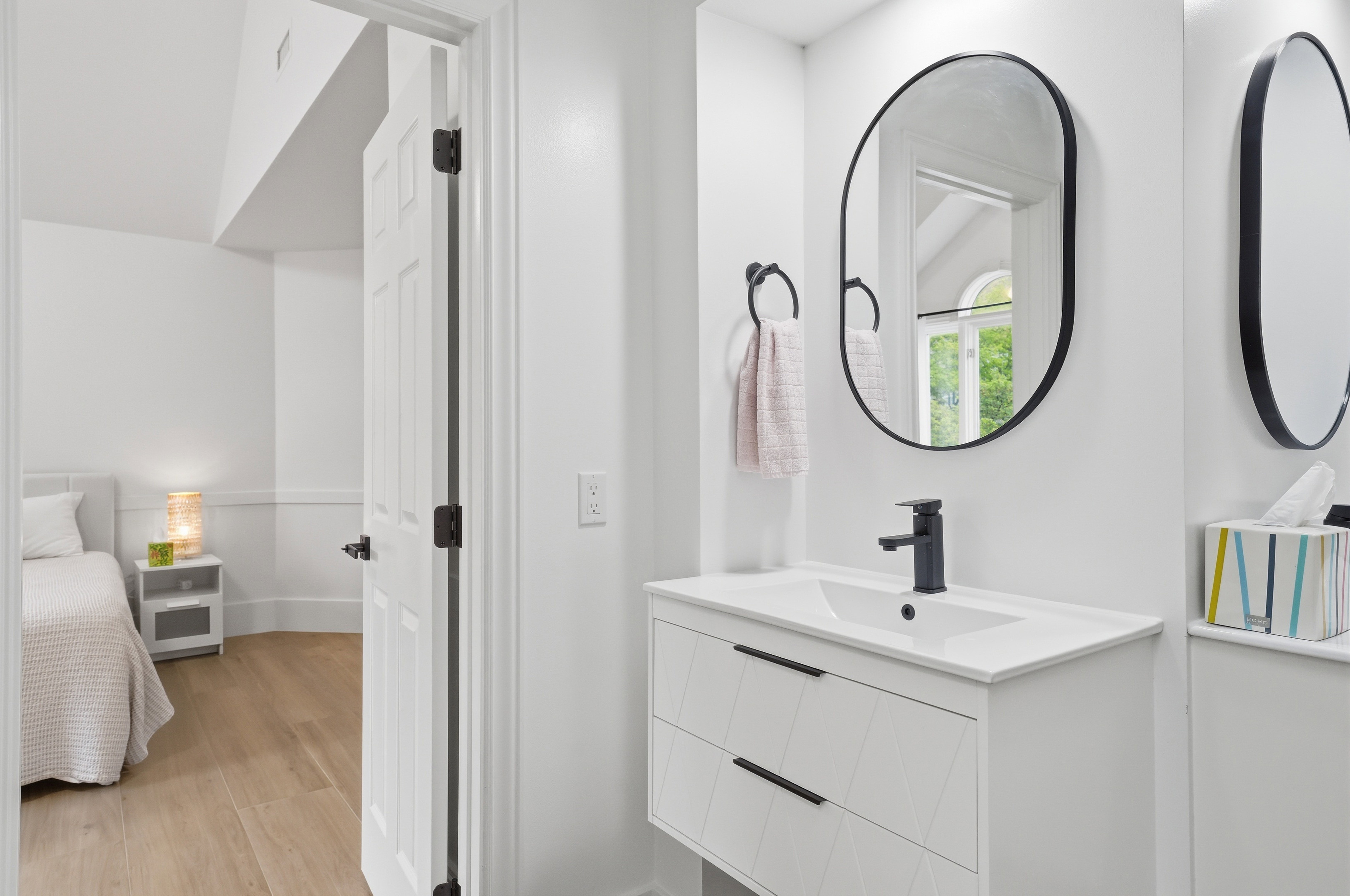 Modern vanity featuring a rectangular integrated sink, matte black faucet, and a black-framed oval mirror