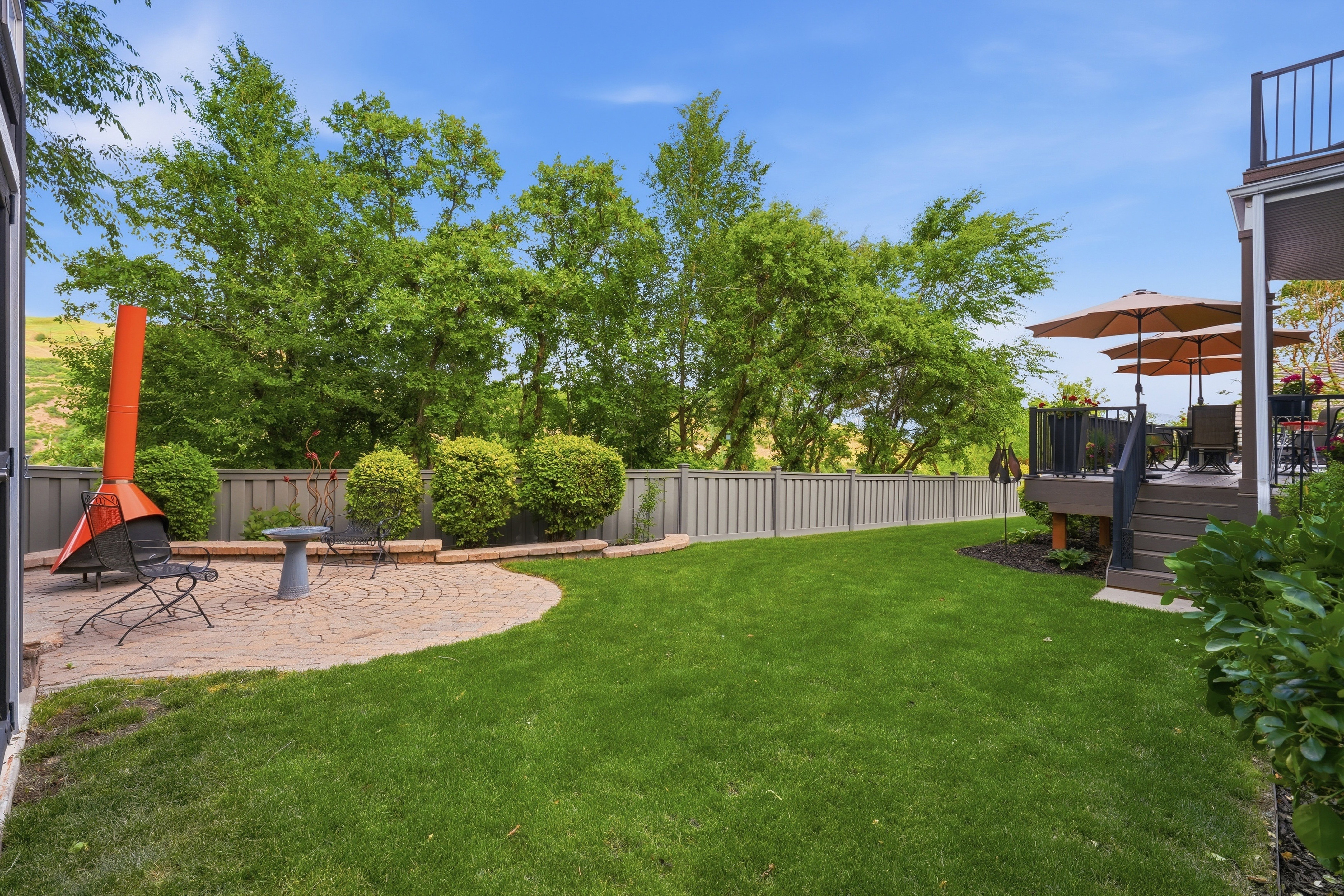 Expansive green lawn with a paver patio featuring a fire pit