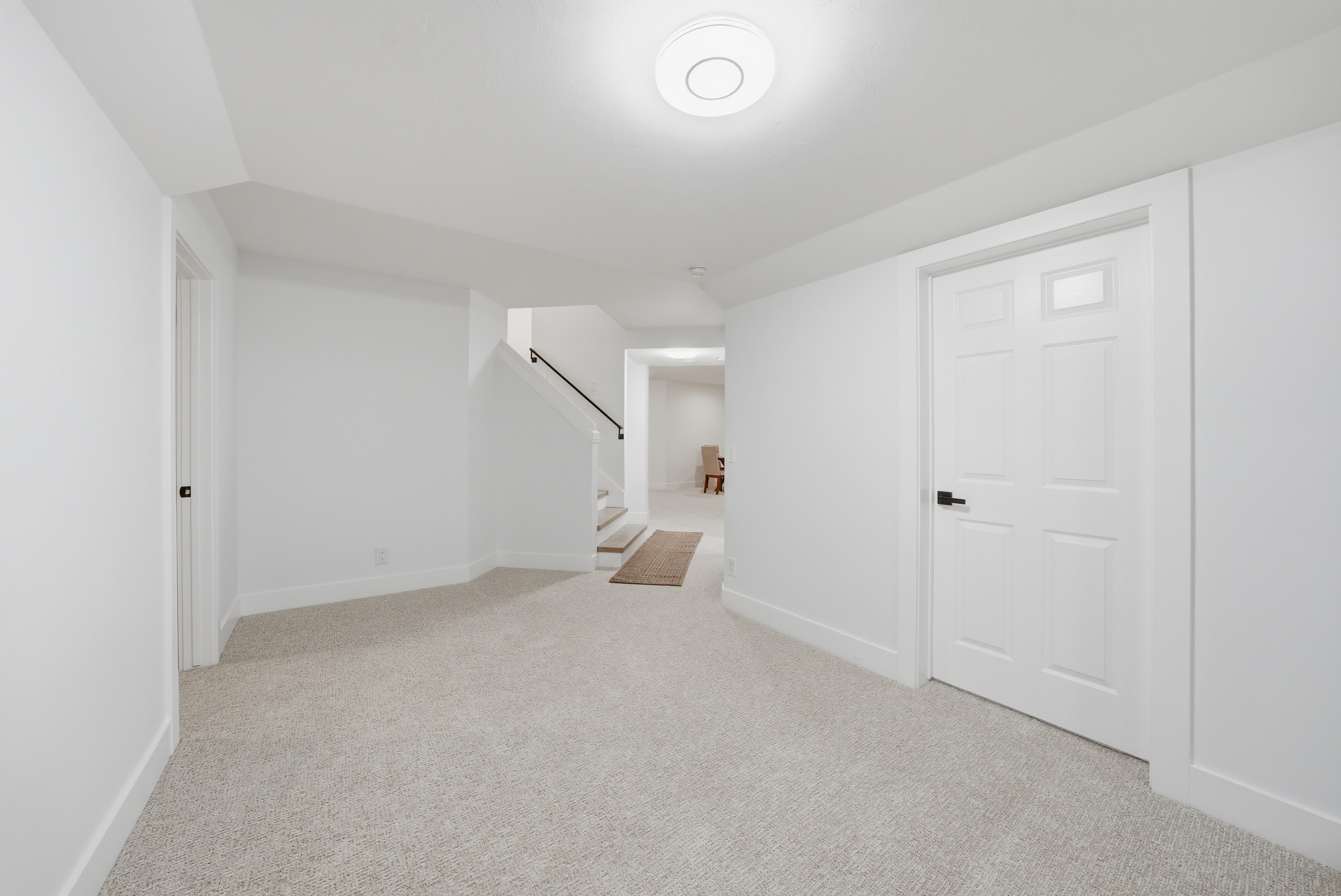 Expansive open space featuring light-colored carpeting, white walls, and a recessed ceiling light