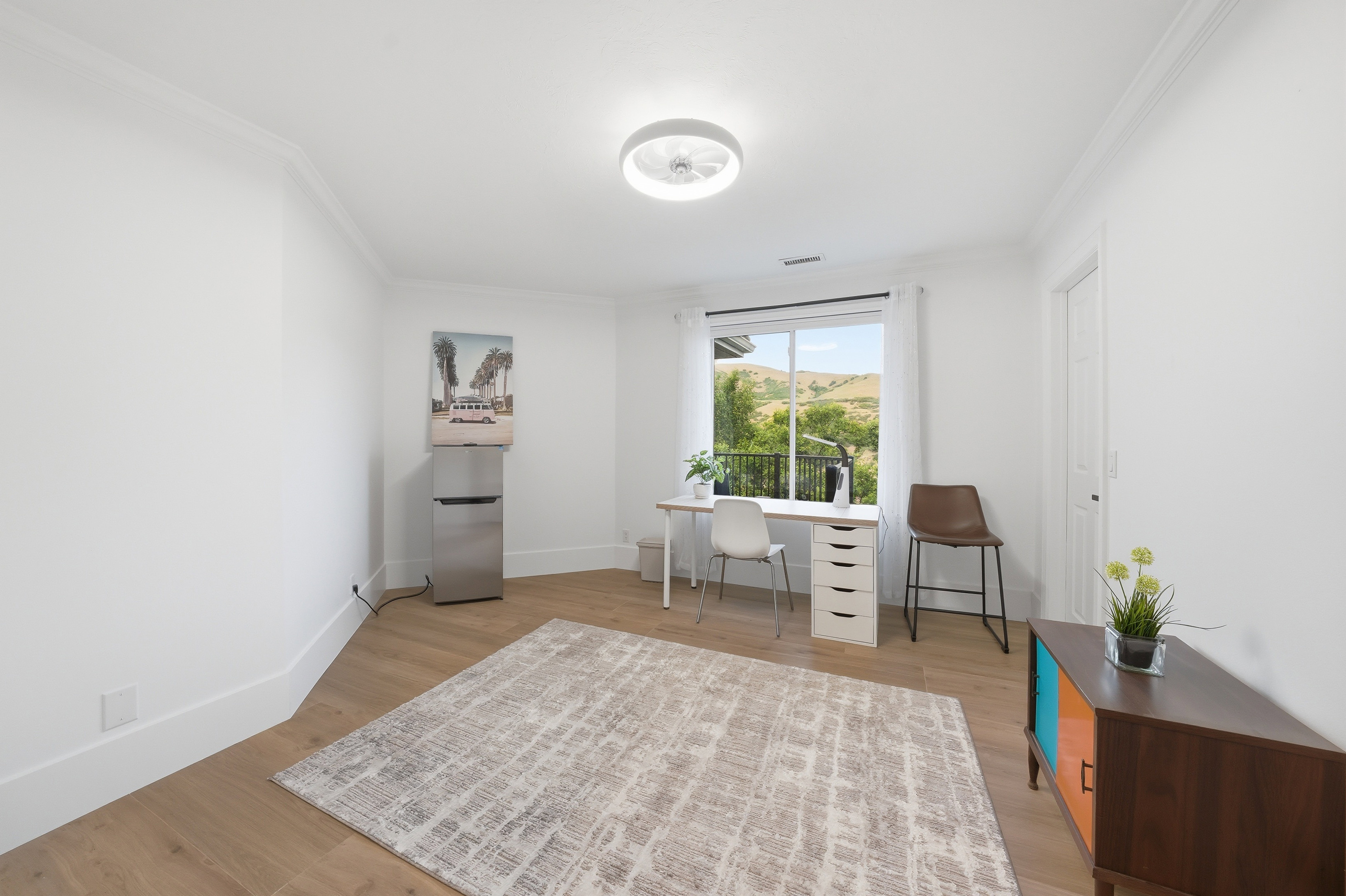 Room featuring wood-finish flooring, a contemporary ceiling light fixture, white crown molding, and a window with a mountain backdrop