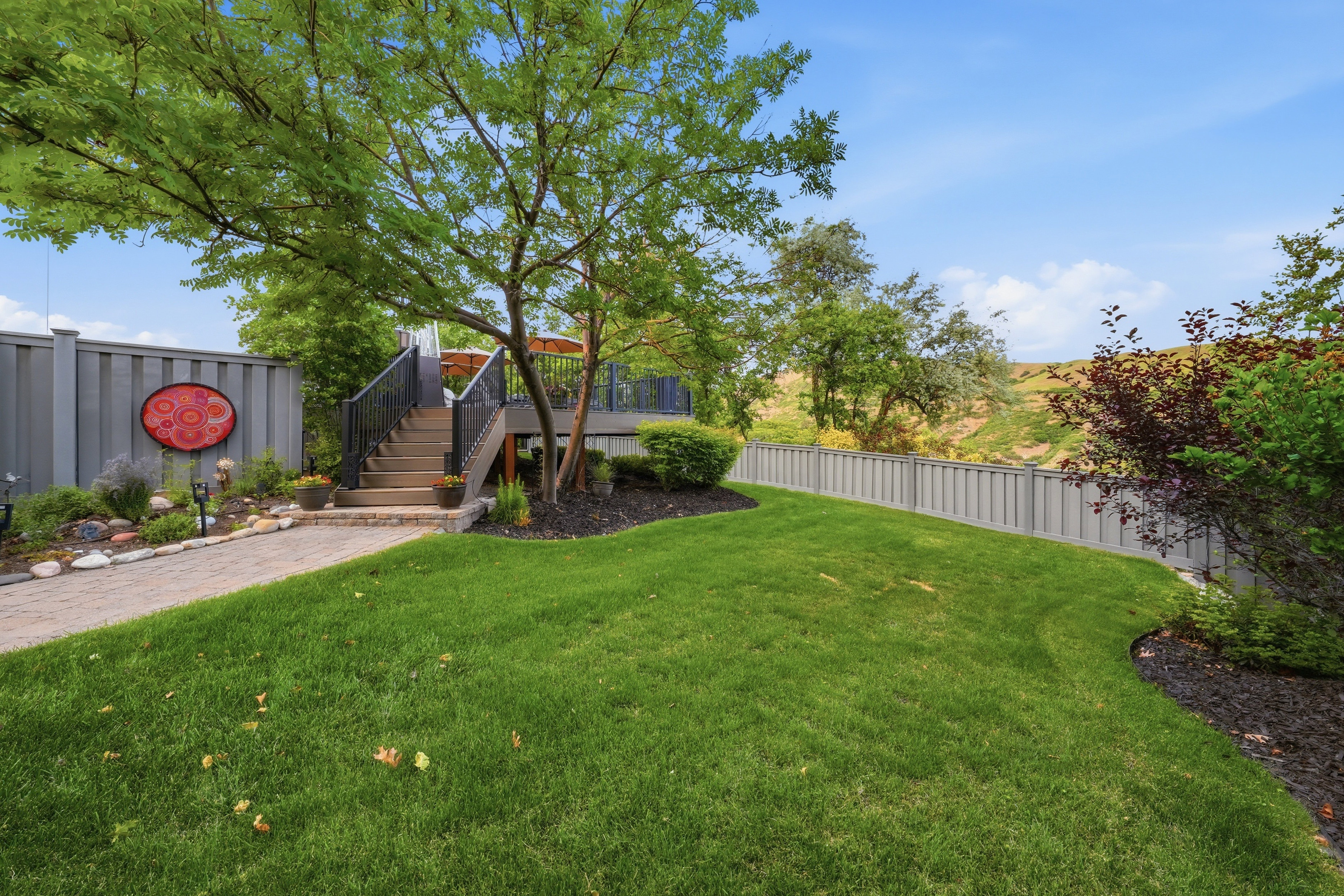 Landscaped backyard featuring a staircase leading to an upper deck