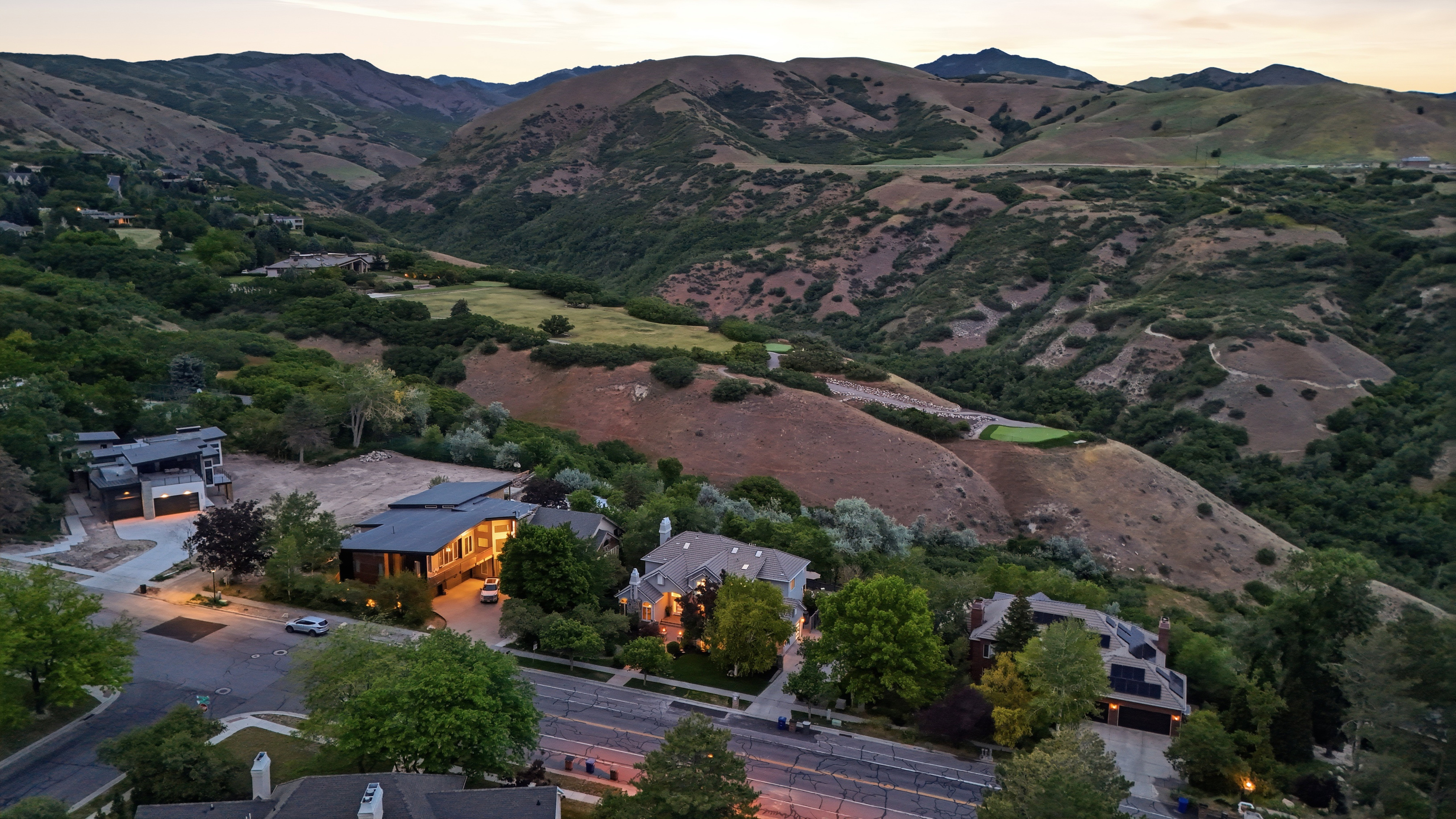 Aerial perspective showcasing multiple properties nestled against a backdrop of verdant hills and distant mountains