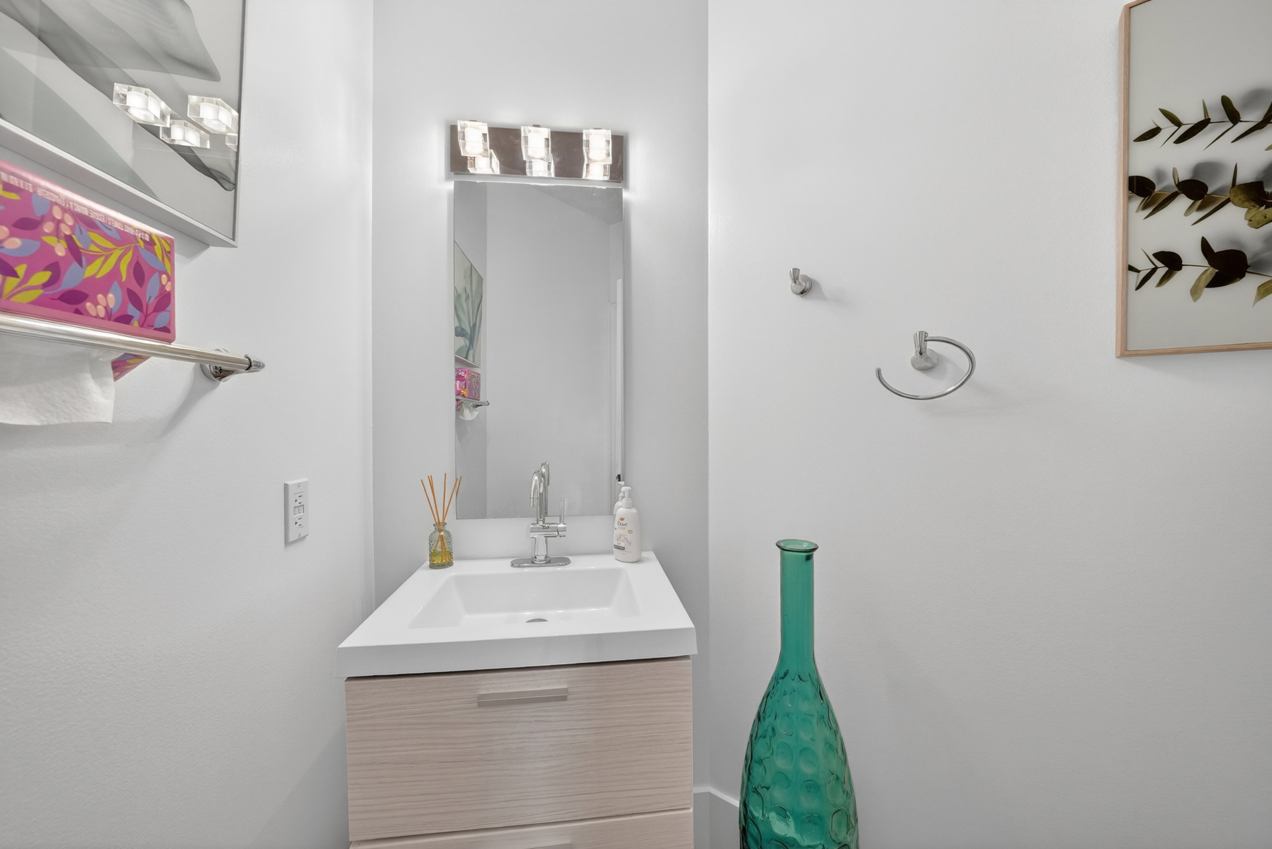 Modern vanity featuring a white countertop and integrated sink, underlit by a contemporary fixture
