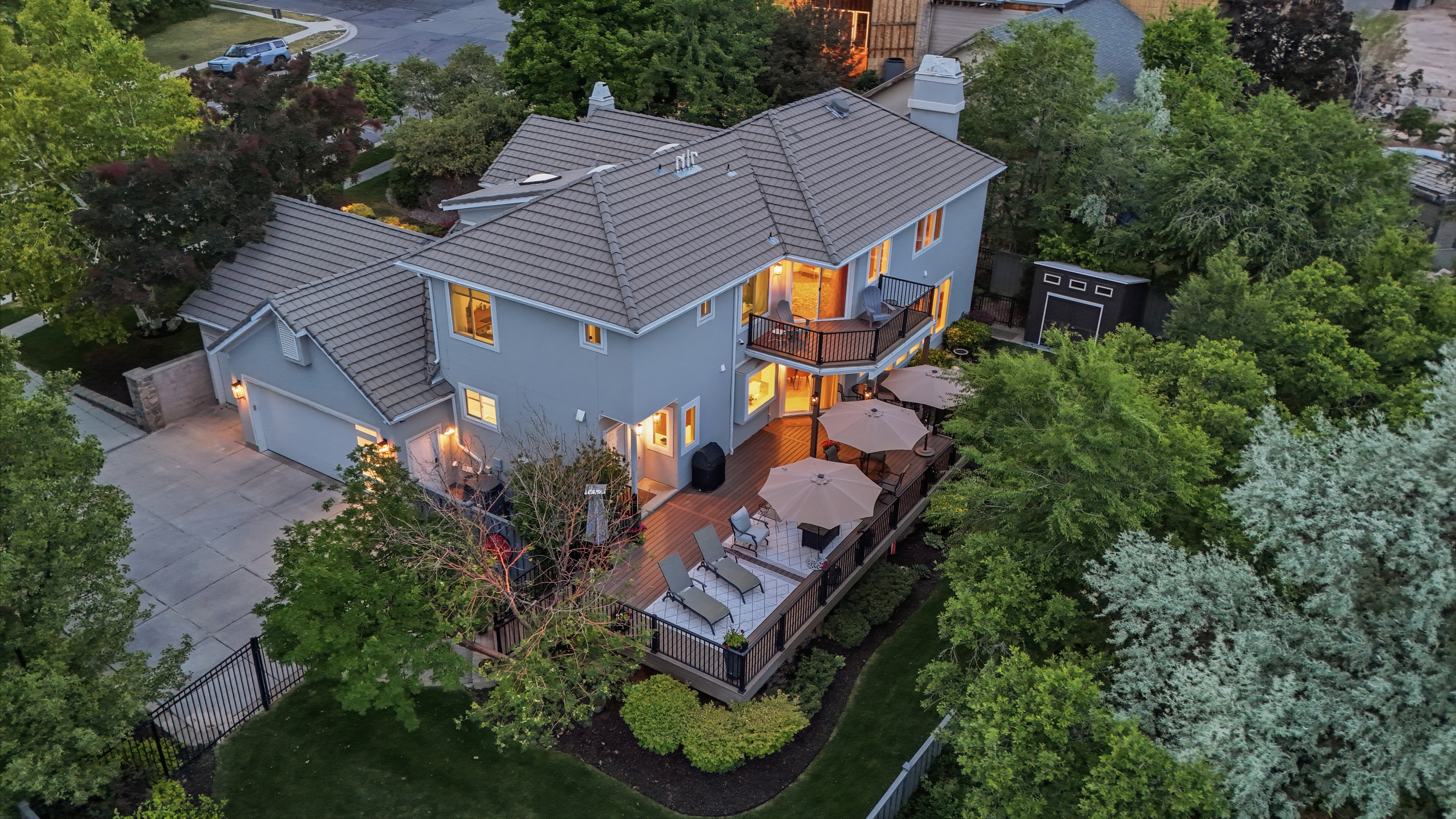 Spacious rear exterior featuring a multi-level wood-finish deck with iron railings