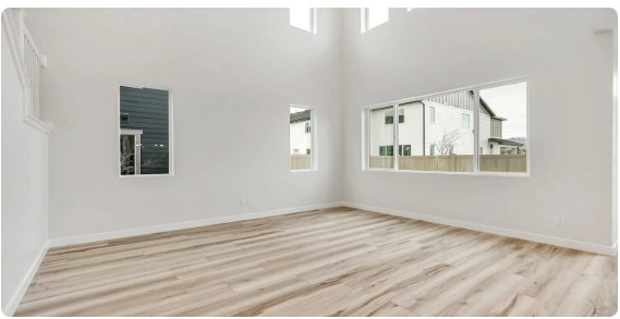 Vaulted ceiling room featuring light wood-finish flooring, white painted walls, and multiple windows
