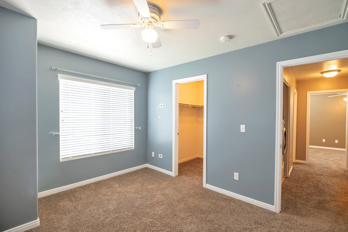 Carpeted room featuring a ceiling fan with integrated lighting, a window with horizontal blinds, and white trim