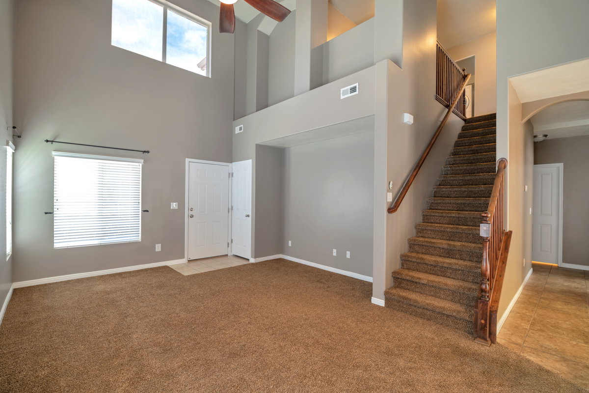 Two-story entry featuring a white panel door, high ceilings, and a decorative ceiling fan