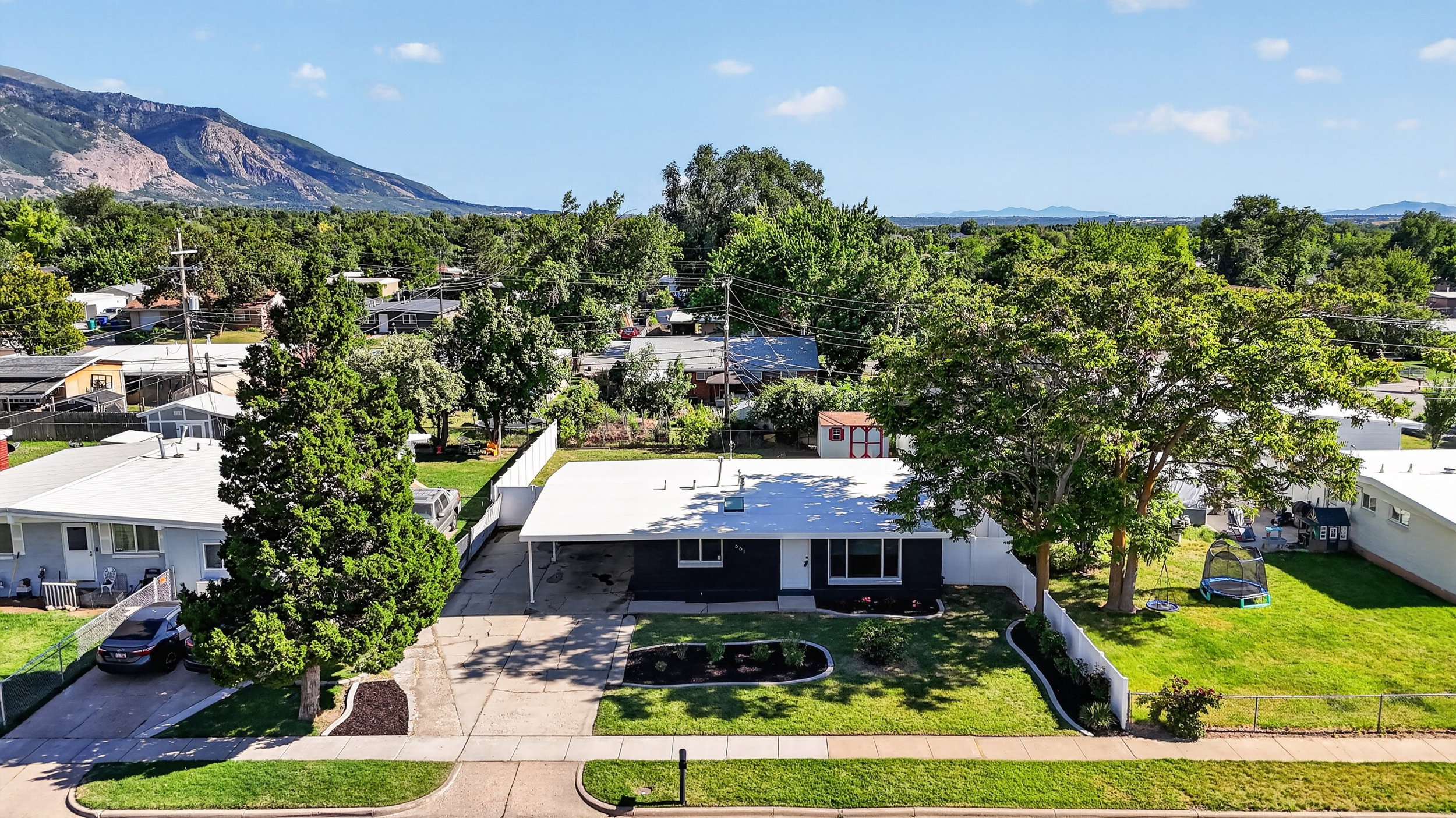Single-story residence featuring a dark exterior with white trim, a carport, and a concrete driveway