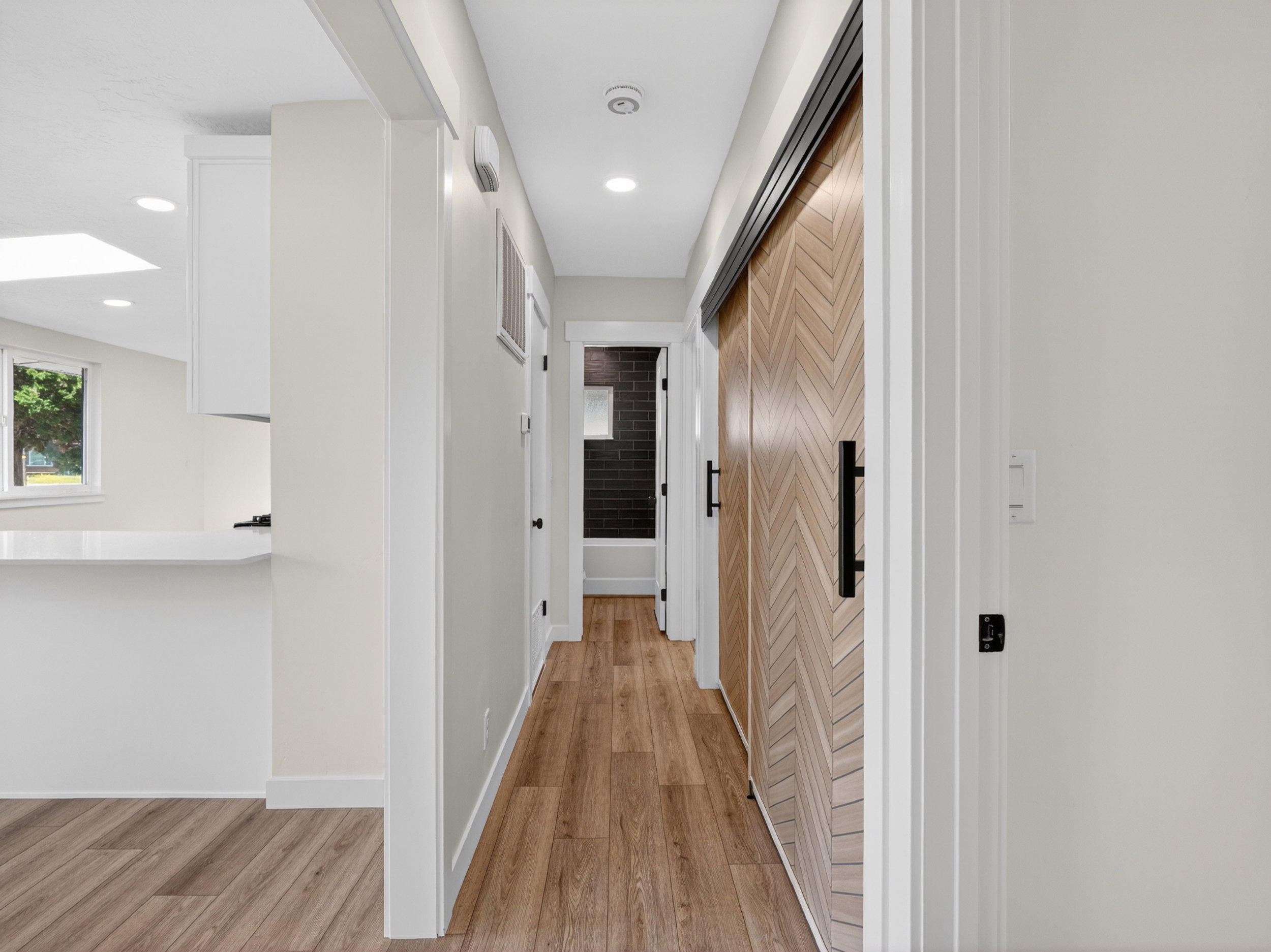 Hallway featuring wood-finish flooring, recessed lighting, and a modern barn door with a chevron pattern